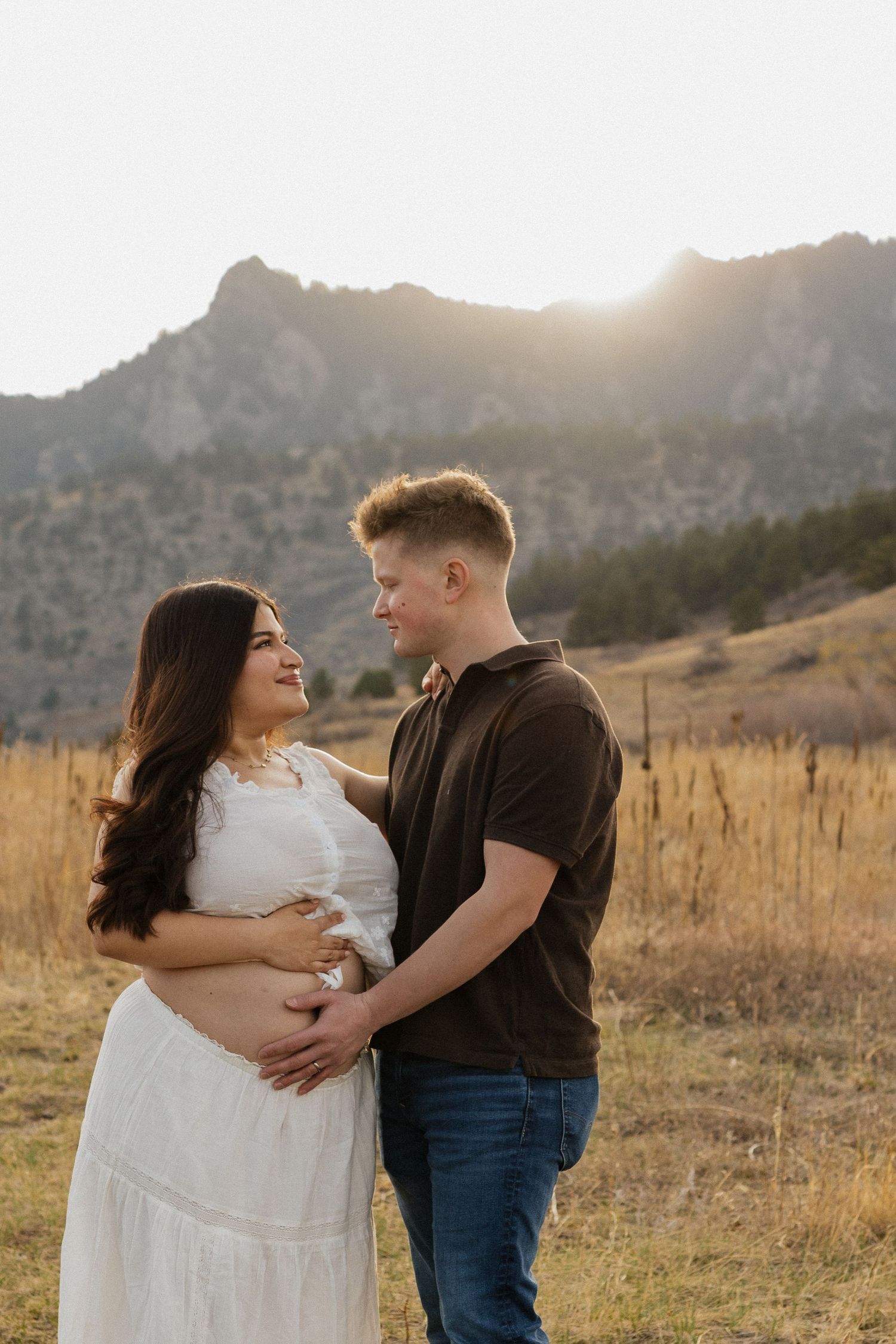 Expecting couple standing together in a Colorado mountain meadow during a warm and natural maternity photography session