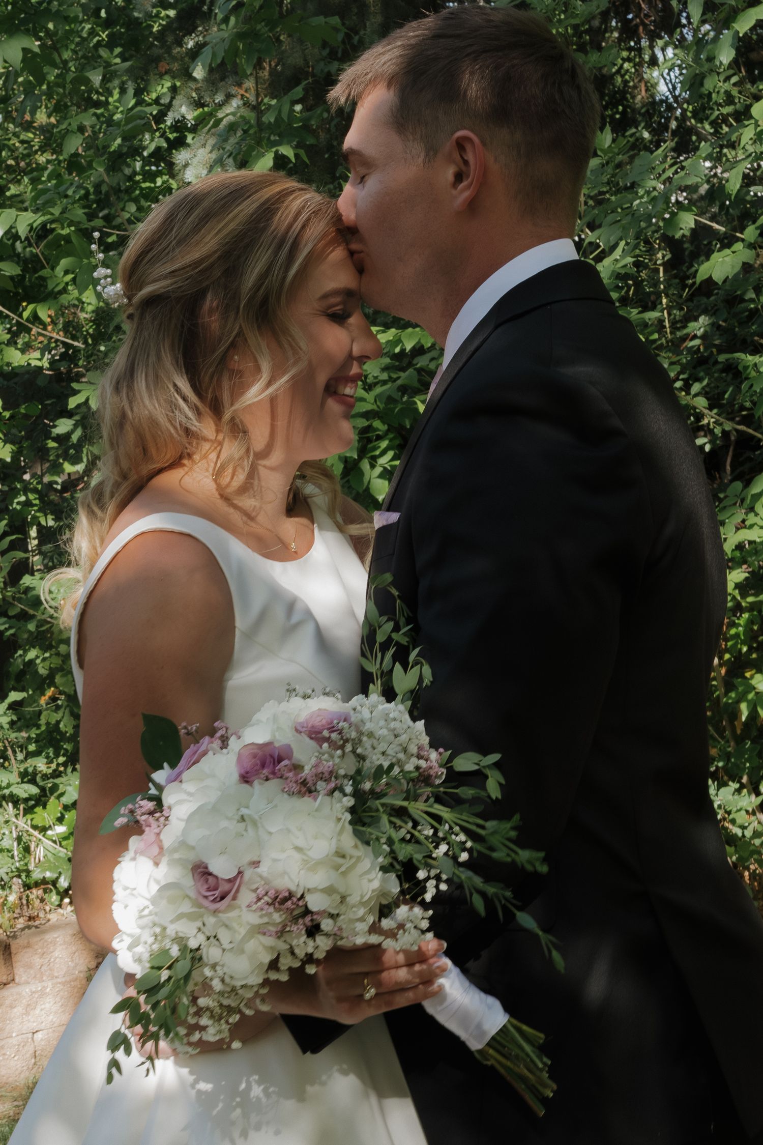 Bride and groom sharing an intimate moment together outdoors on their wedding day