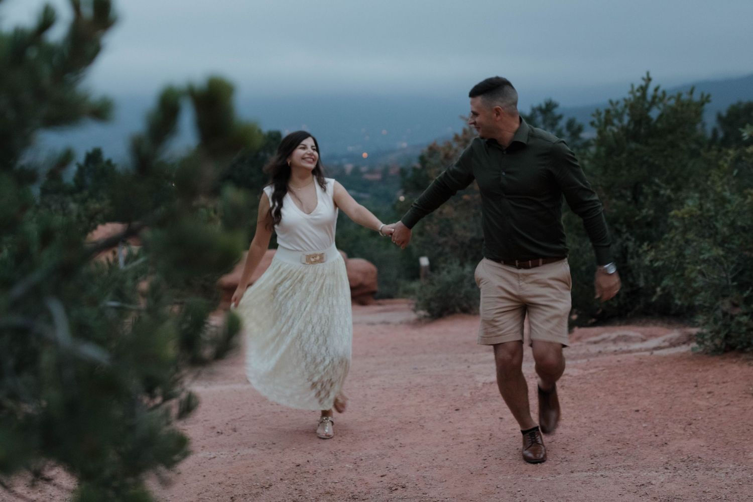 Couple running together through a scenic outdoor trail during a joyful and natural couples photography session