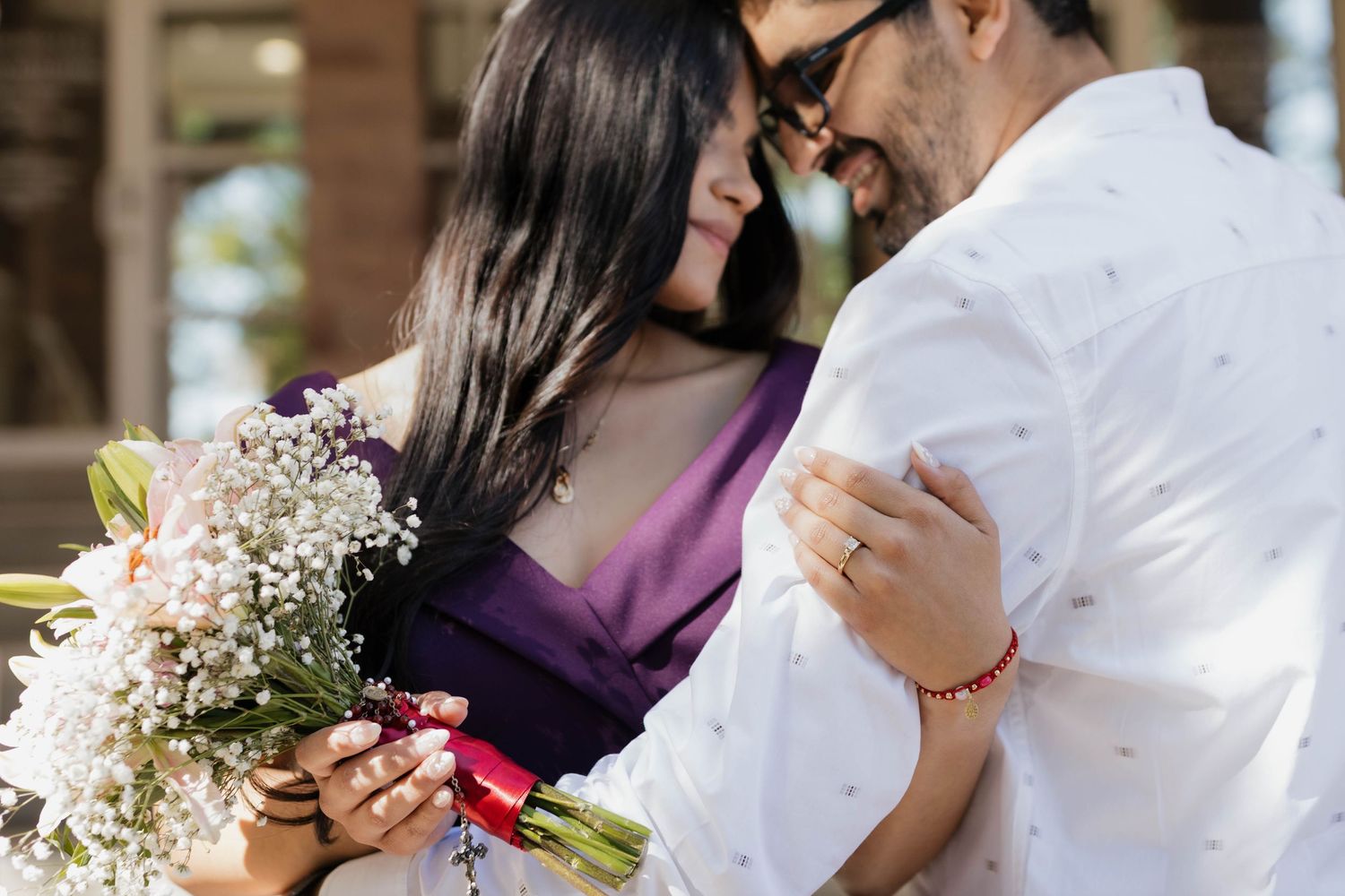 Engaged couple sharing a romantic moment while holding a bouquet of flowers during their engagement session