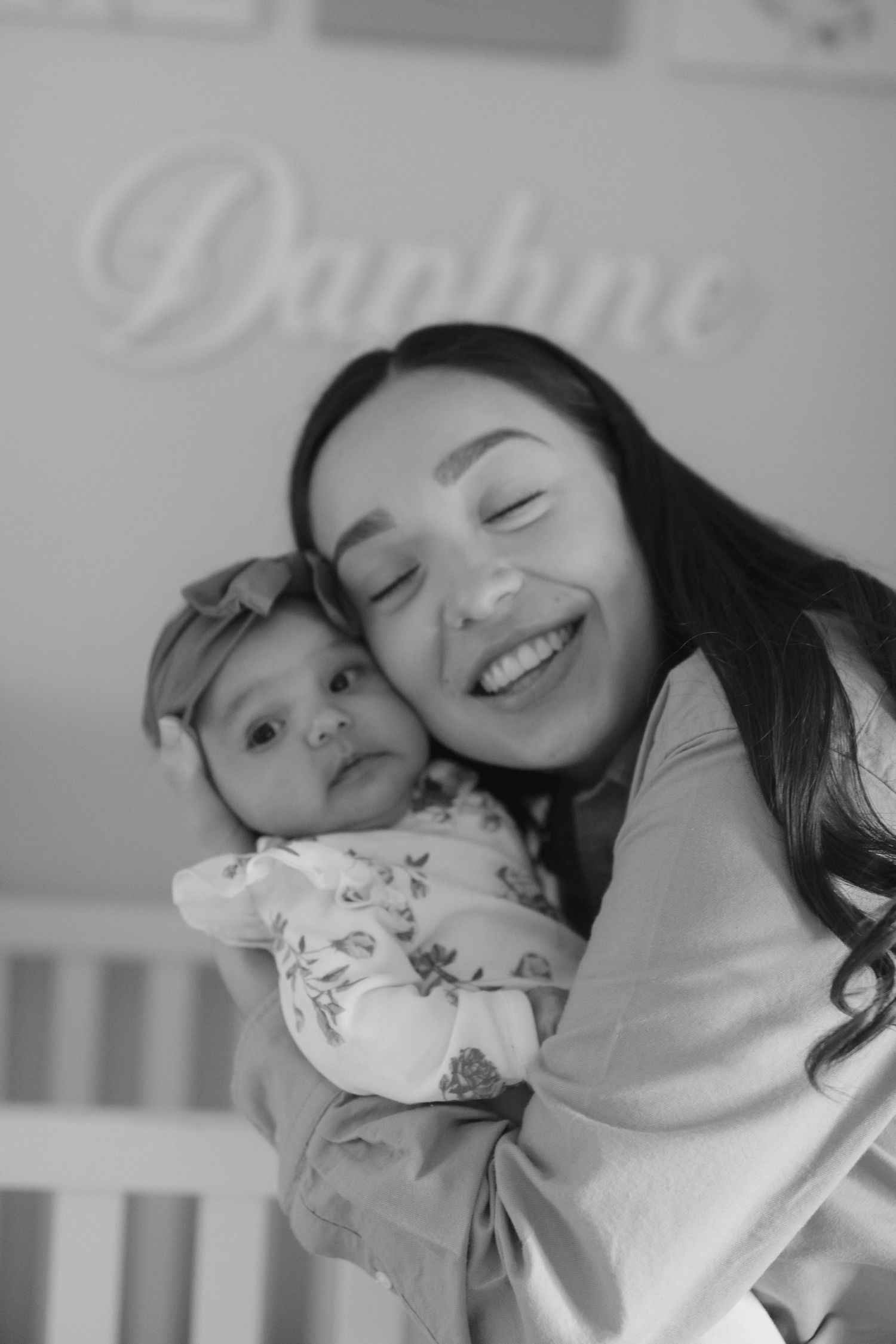 Mother holding her baby and smiling together during a tender black and white maternity photography session