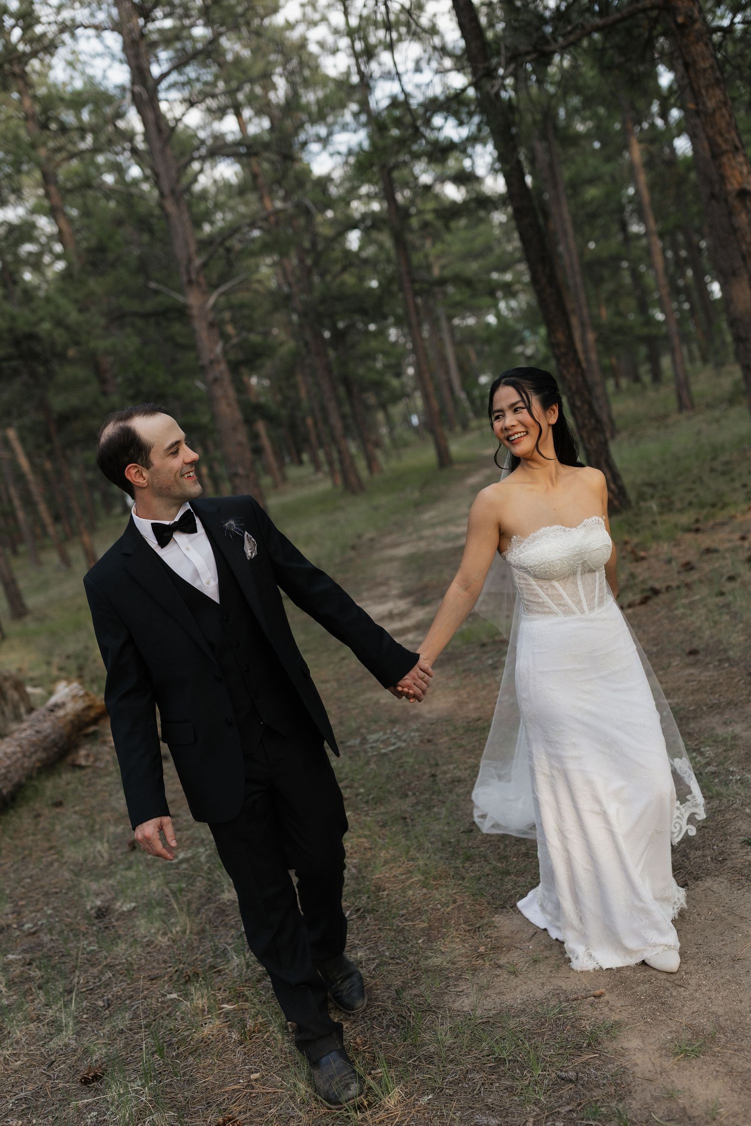 Bride and groom walking hand in hand through the trees after their wedding ceremony