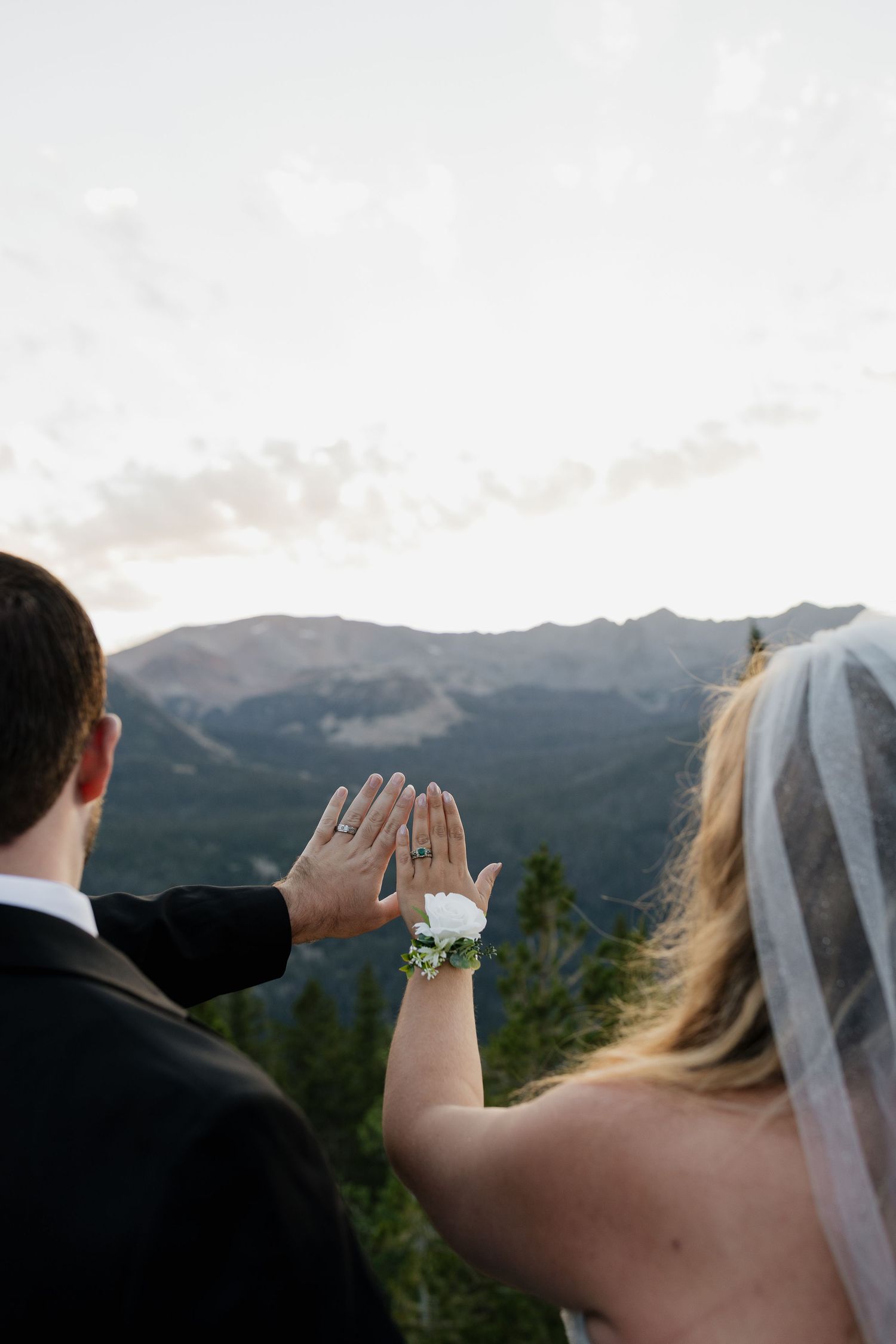Bride and groom holding hands while overlooking a mountain lake