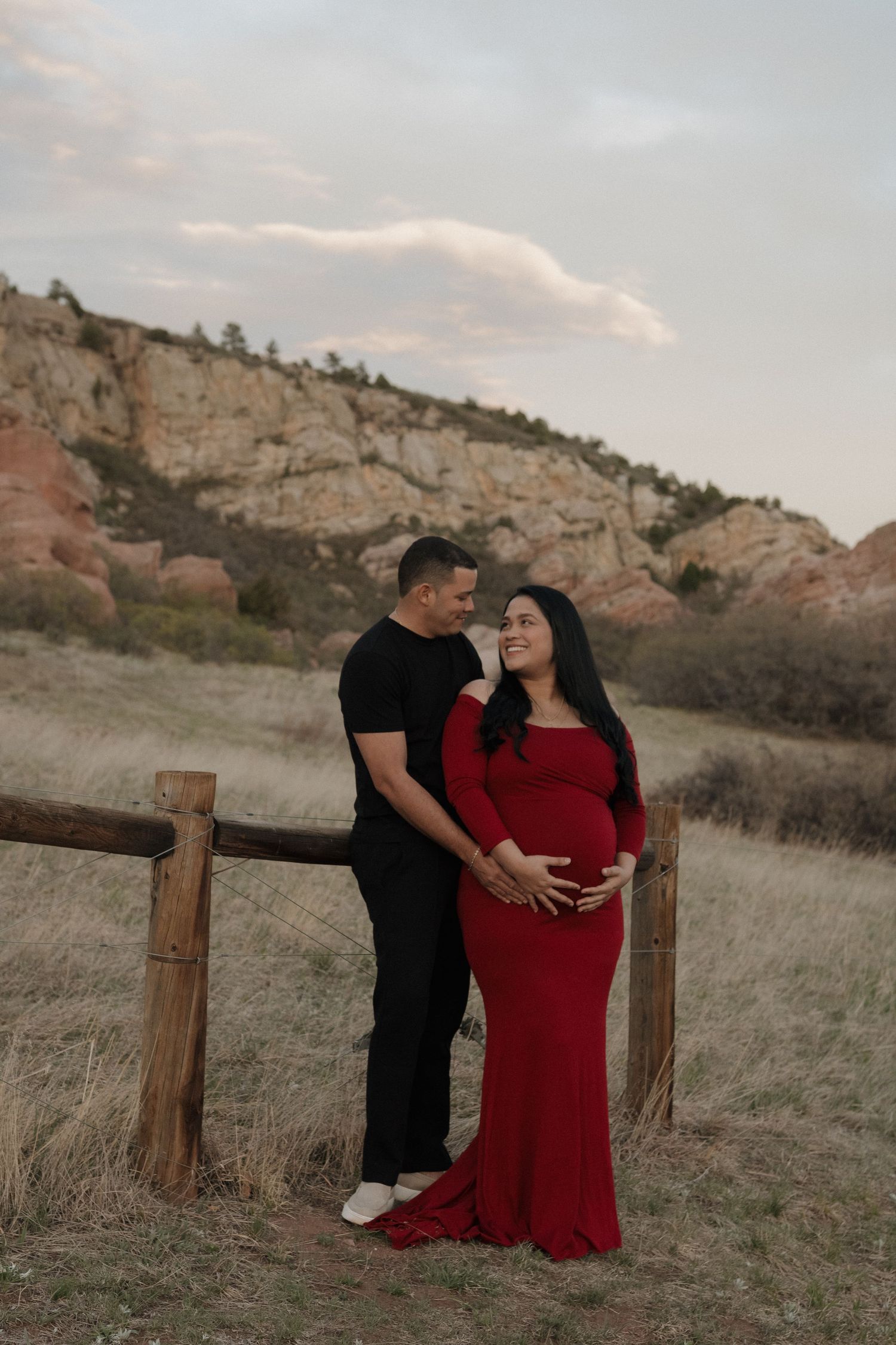 Expecting couple embracing in a scenic landscape during a warm and romantic maternity photography session