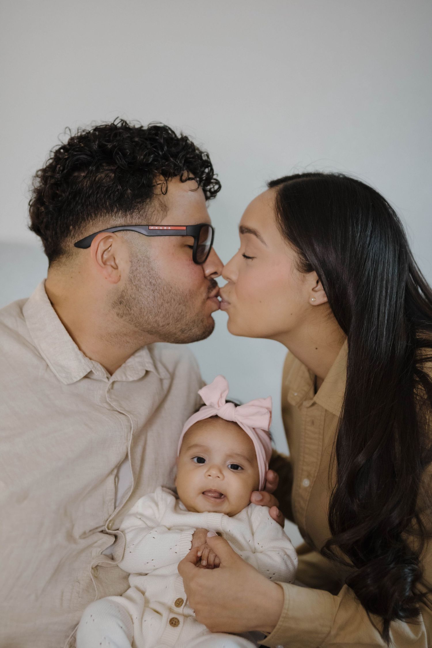 New parents holding their newborn baby and sharing a tender moment together during an intimate maternity photography session