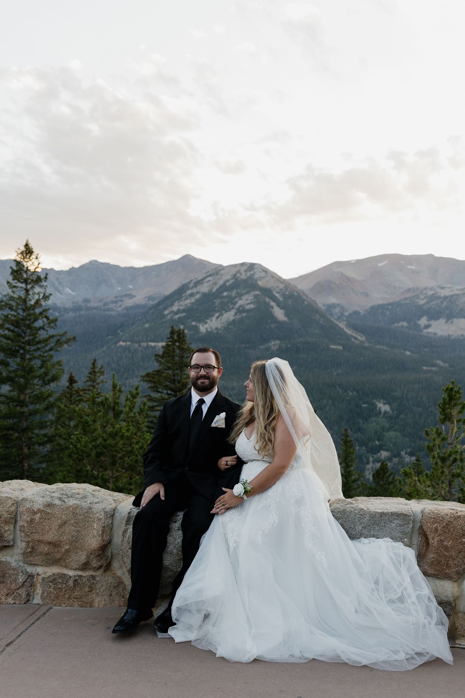 Bride and groom embracing outdoors with mountains in the background
