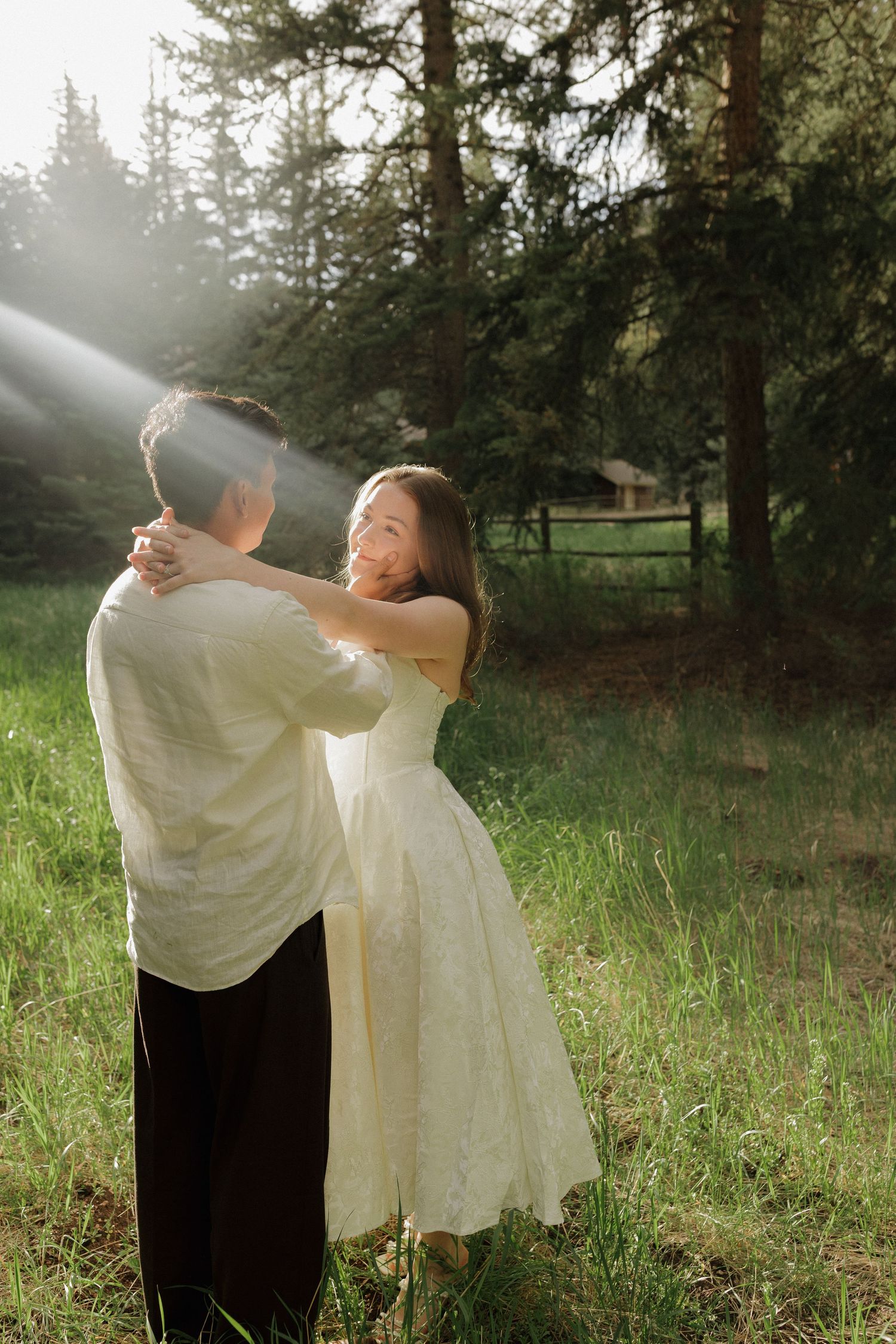 Couple embracing in a sunlit forest during a romantic outdoor couples photography session