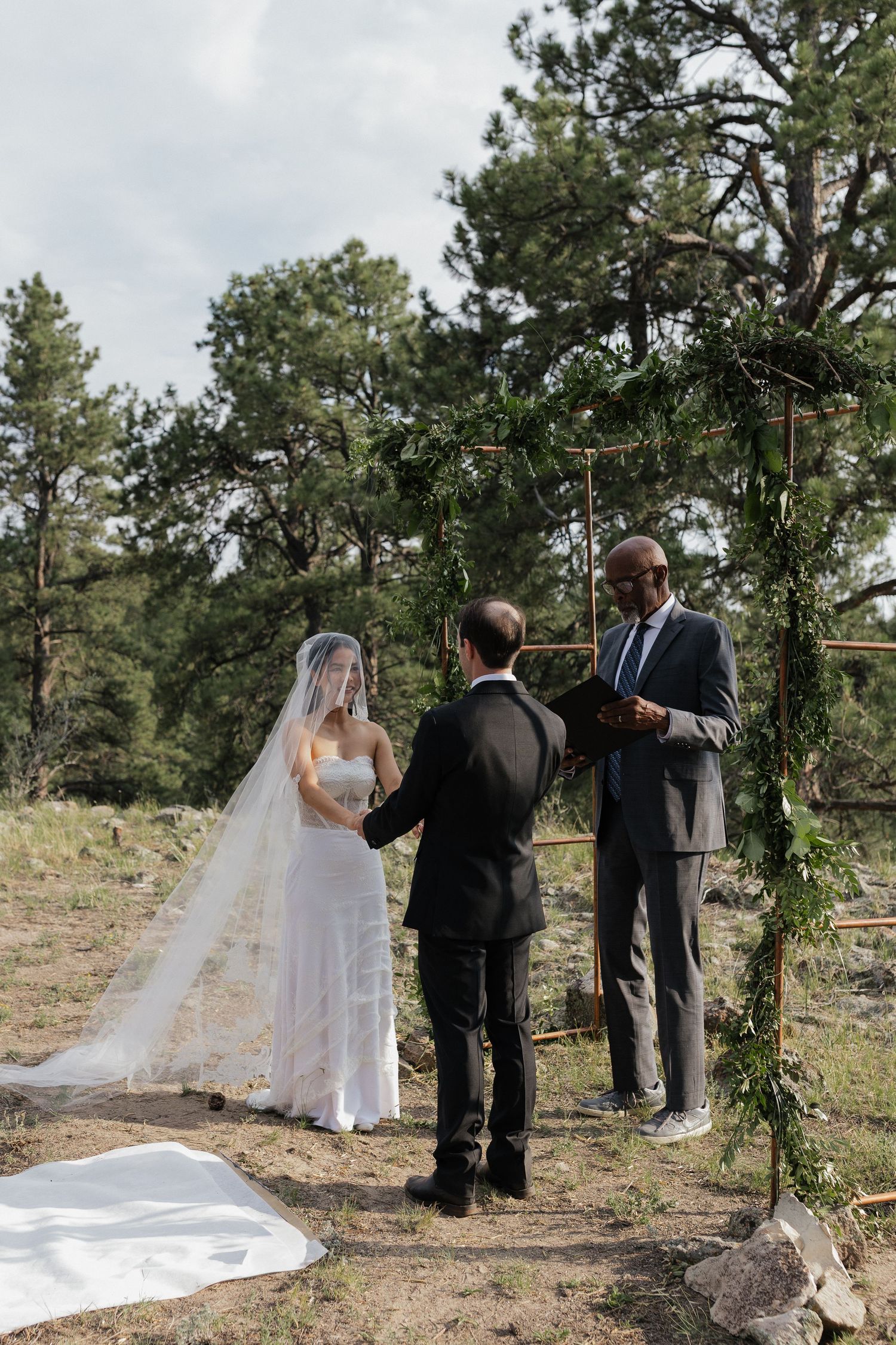 Bride and groom standing together during an outdoor wedding ceremony with their officiant