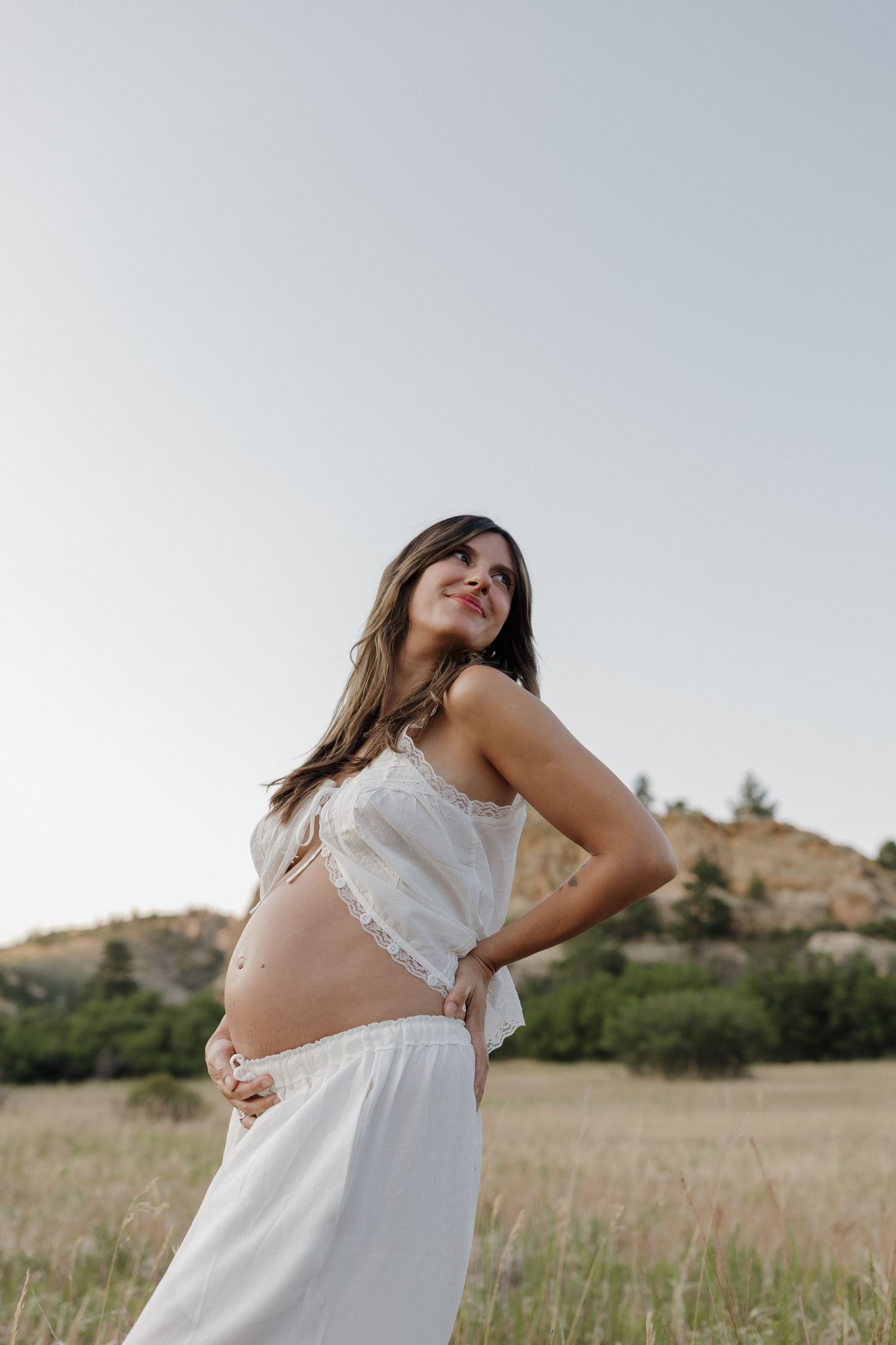 Pregnant woman standing outdoors in a natural maternity portrait session