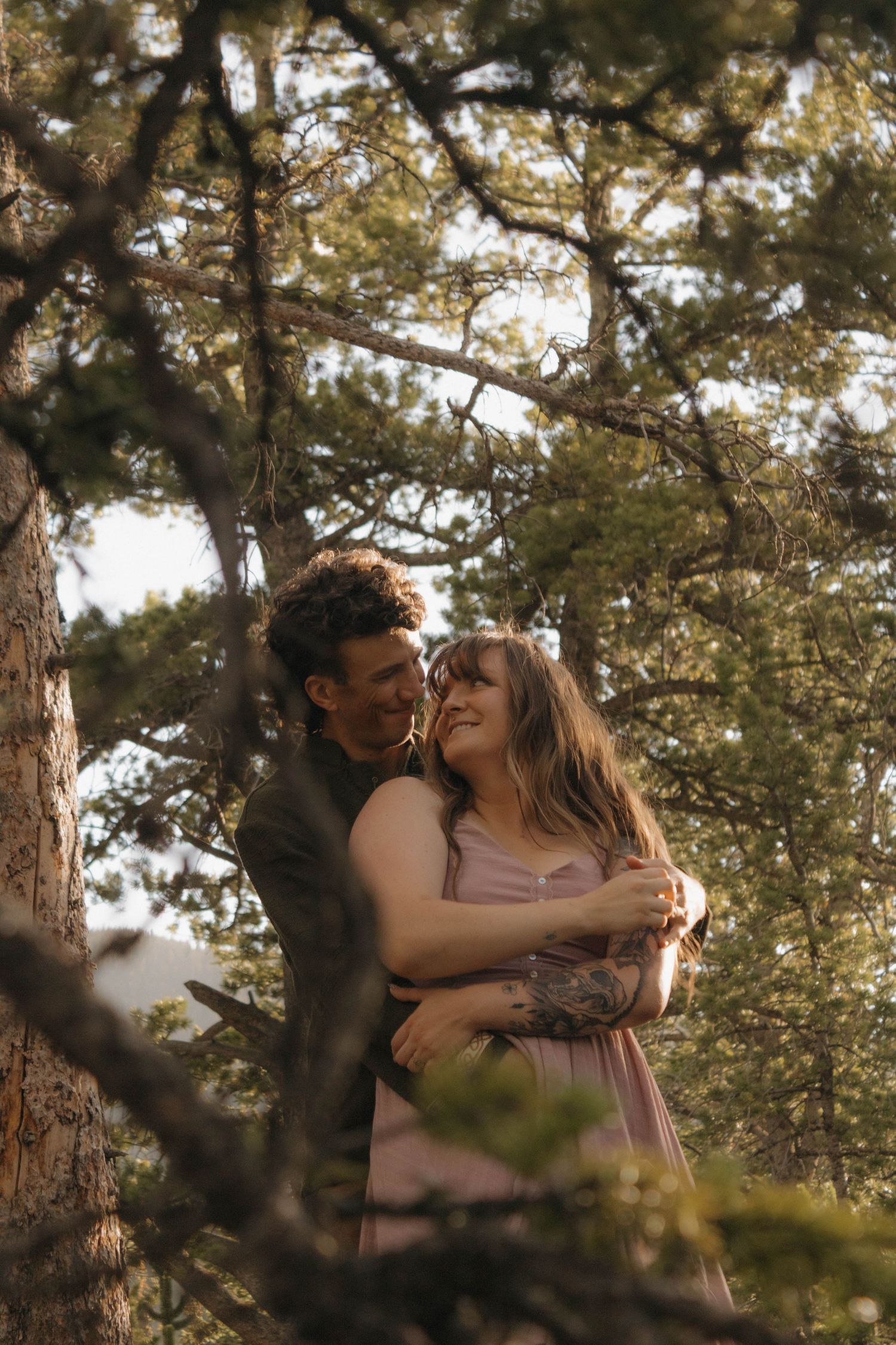 Couple embracing among tall trees during an intimate and romantic couples photography session