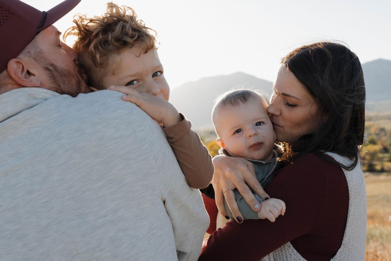 Family of four cuddling together outdoors during a natural and intimate family photography session
