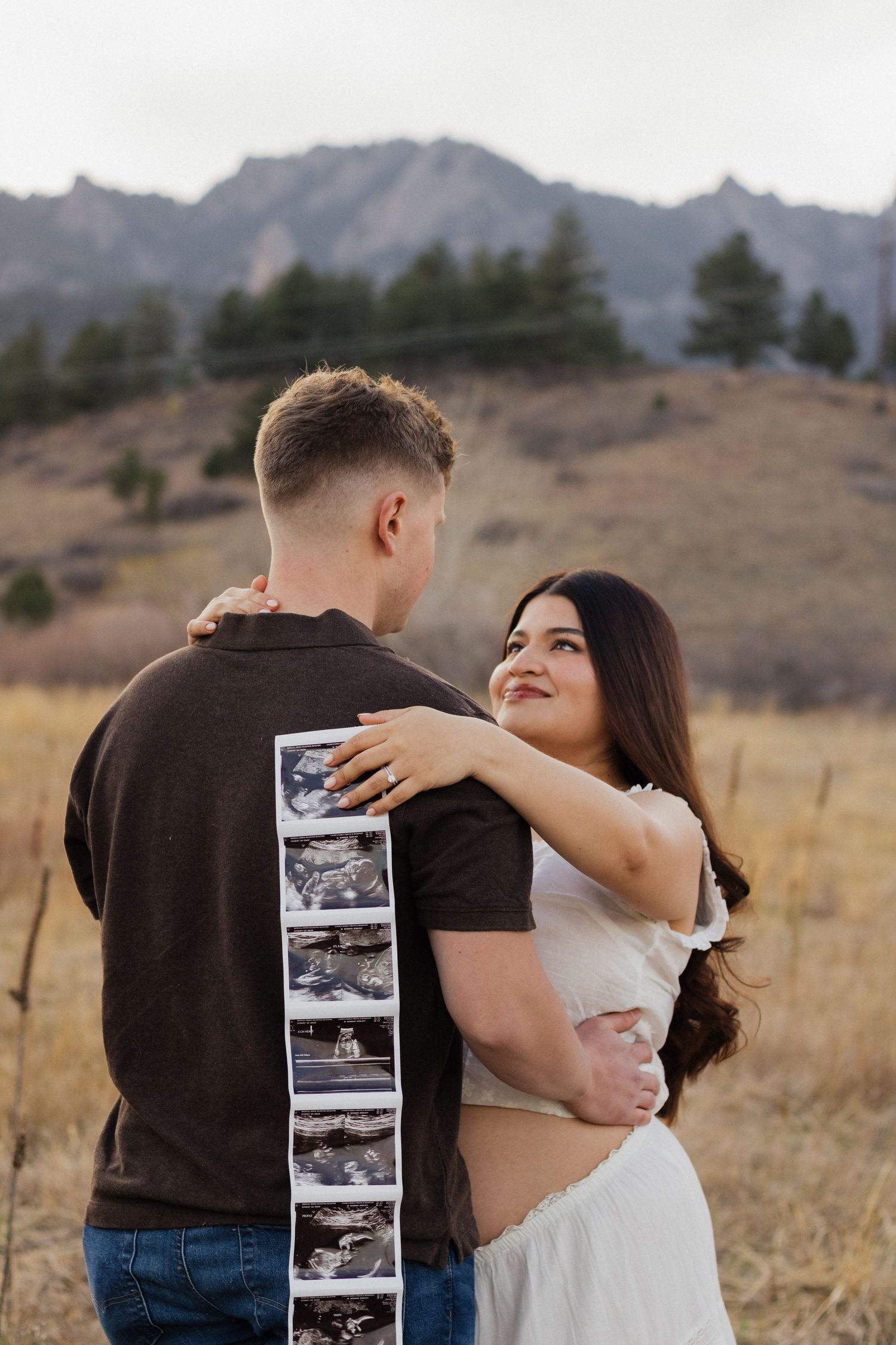 Expecting couple embracing outdoors mountain meadow during a natural maternity photography session