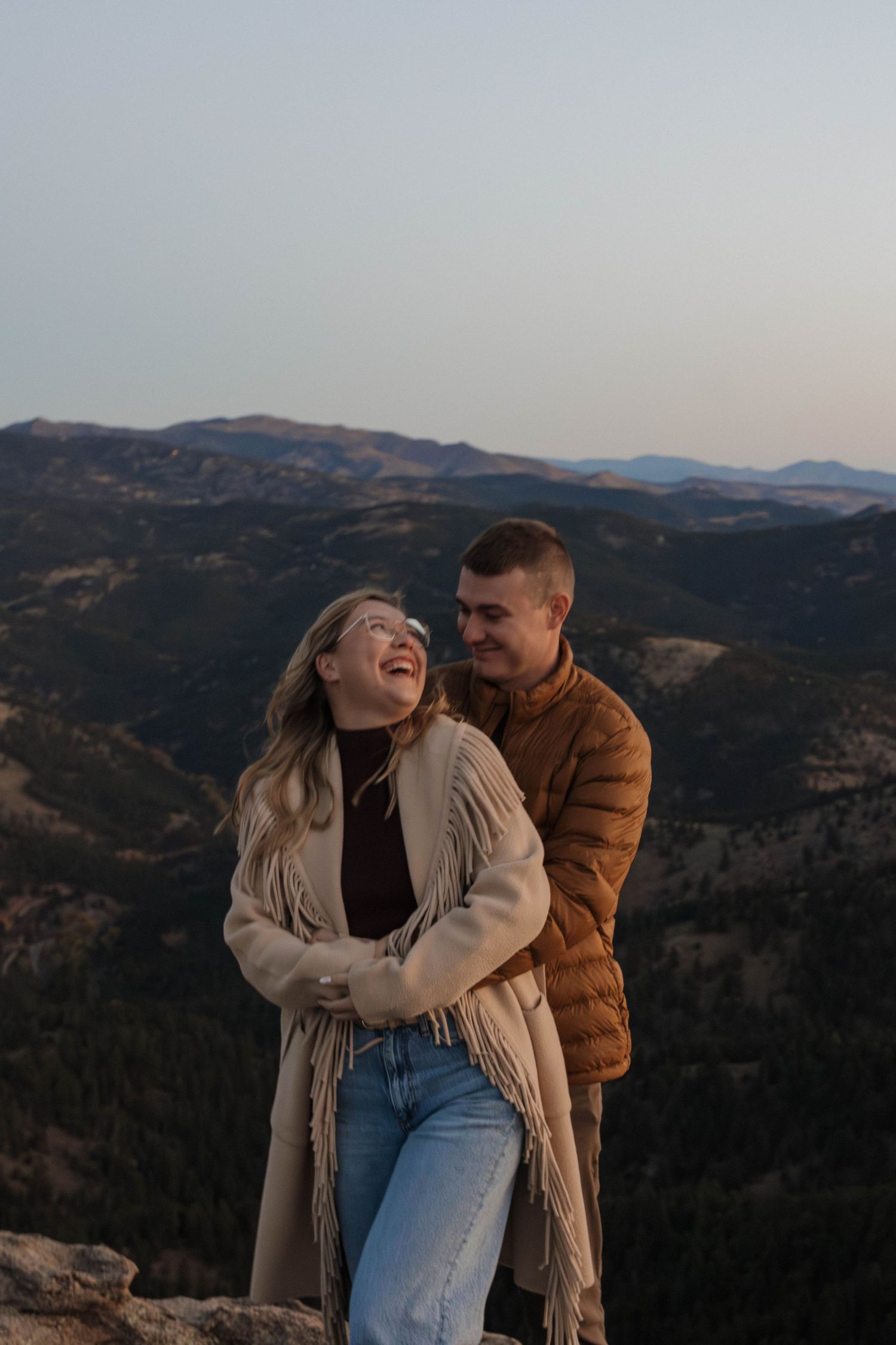 Couple embracing outdoors with a mountain landscape in the background during a warm and natural couples photography session
