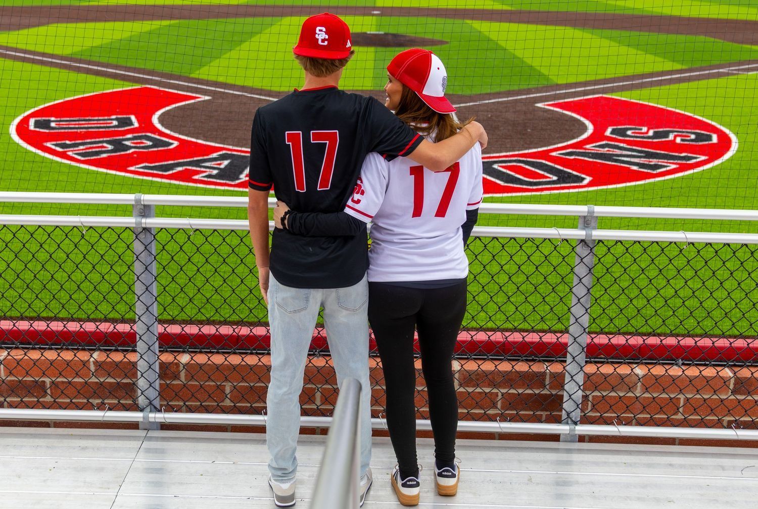 Couple in matching #17 jerseys looking out over the Swartz Creek Dragons baseball field