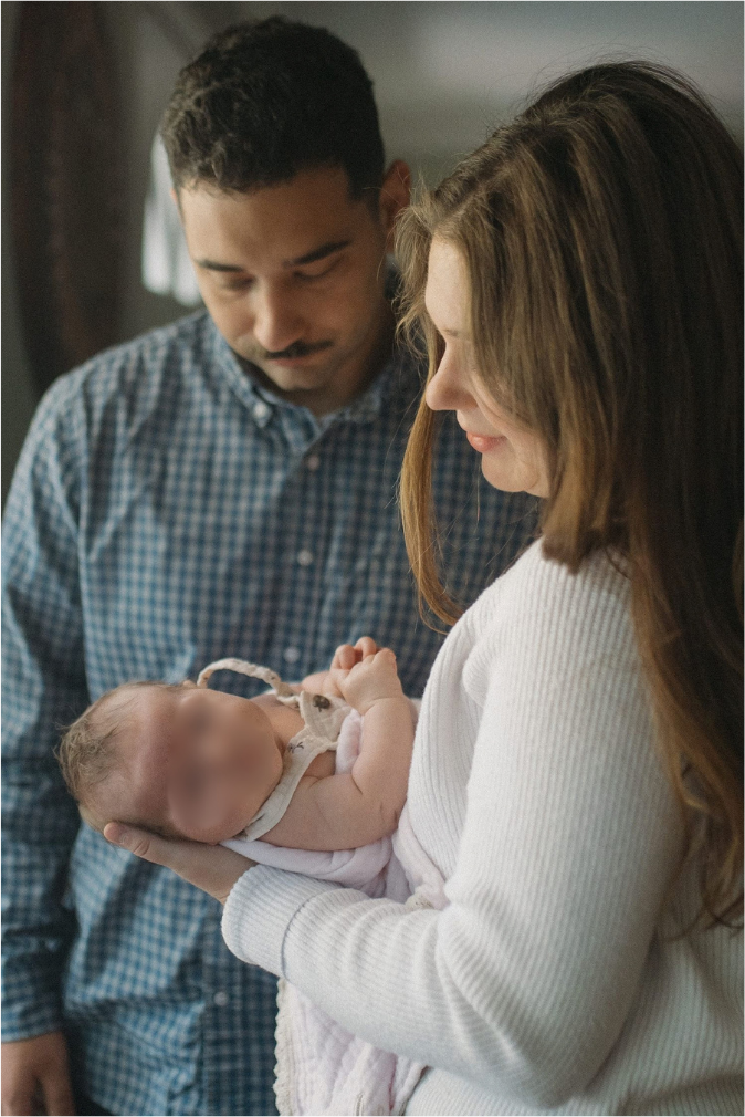 New parents lovingly gaze at their newborn baby during an intimate family portrait session.