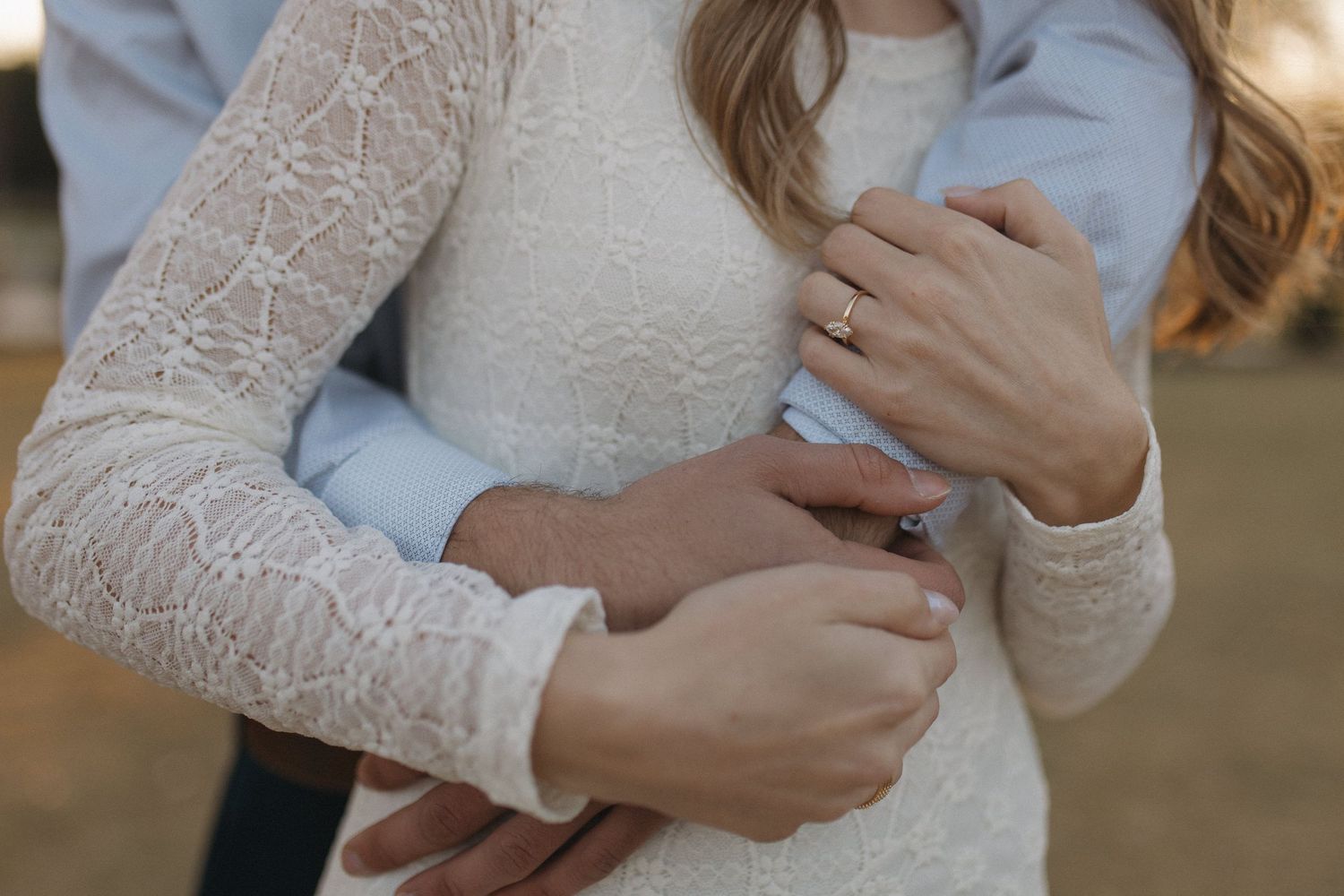Close-up of an engaged couple embracing, showcasing a diamond ring on the womans hand.
