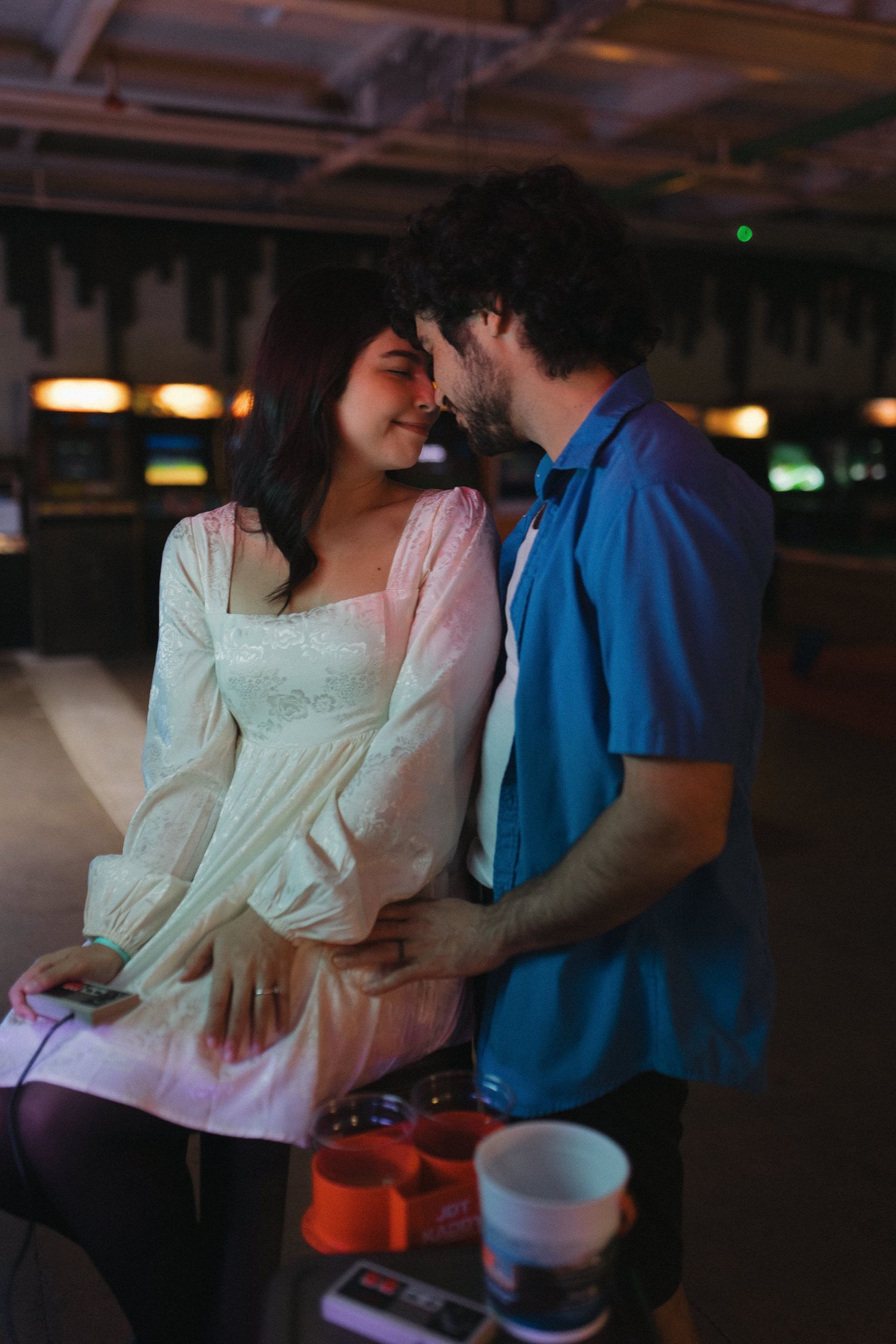 Romantic couple shares an intimate moment at a dimly lit bowling alley.