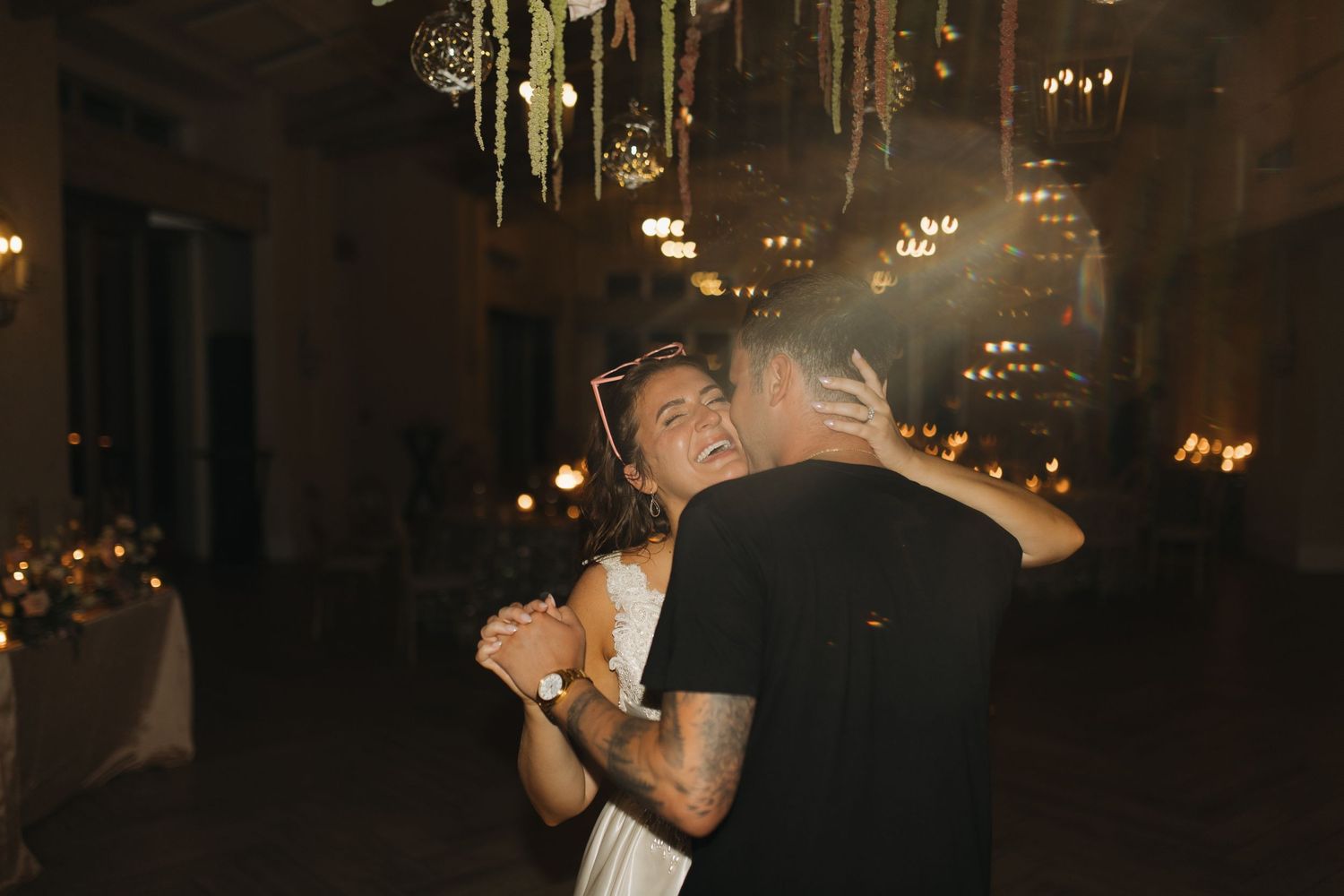 Couple sharing a romantic dance together under warm glowing lights at their wedding reception.