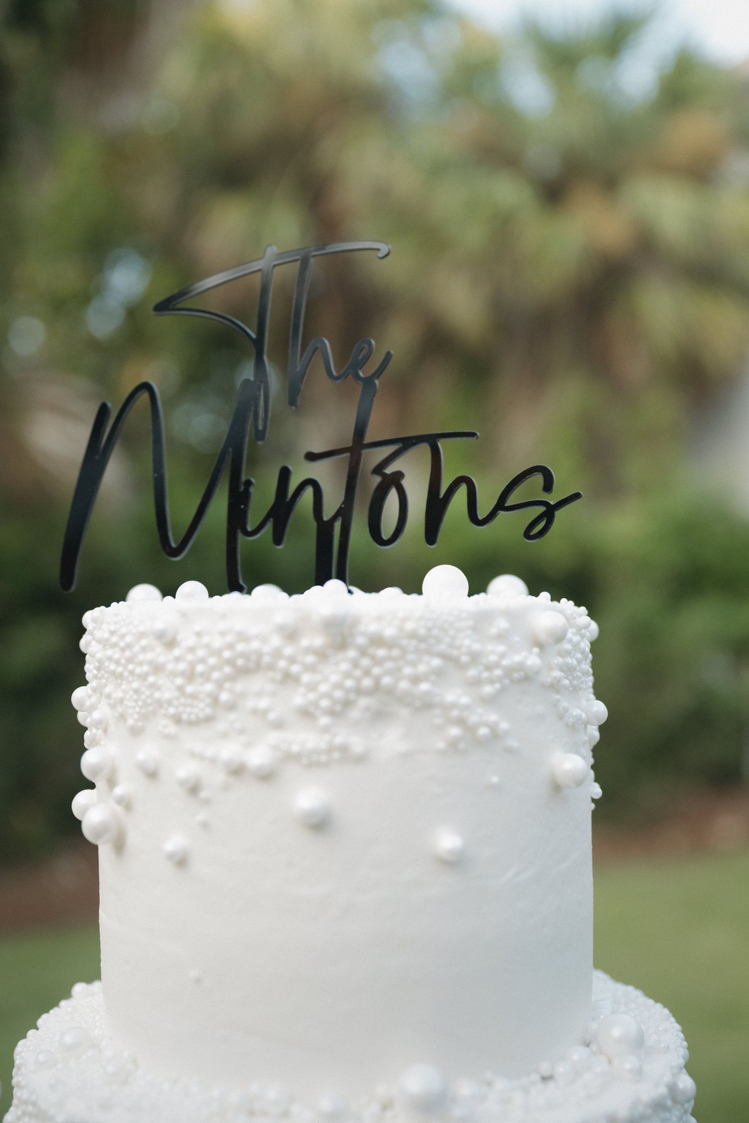 White wedding cake with pearl decorations and black acrylic 