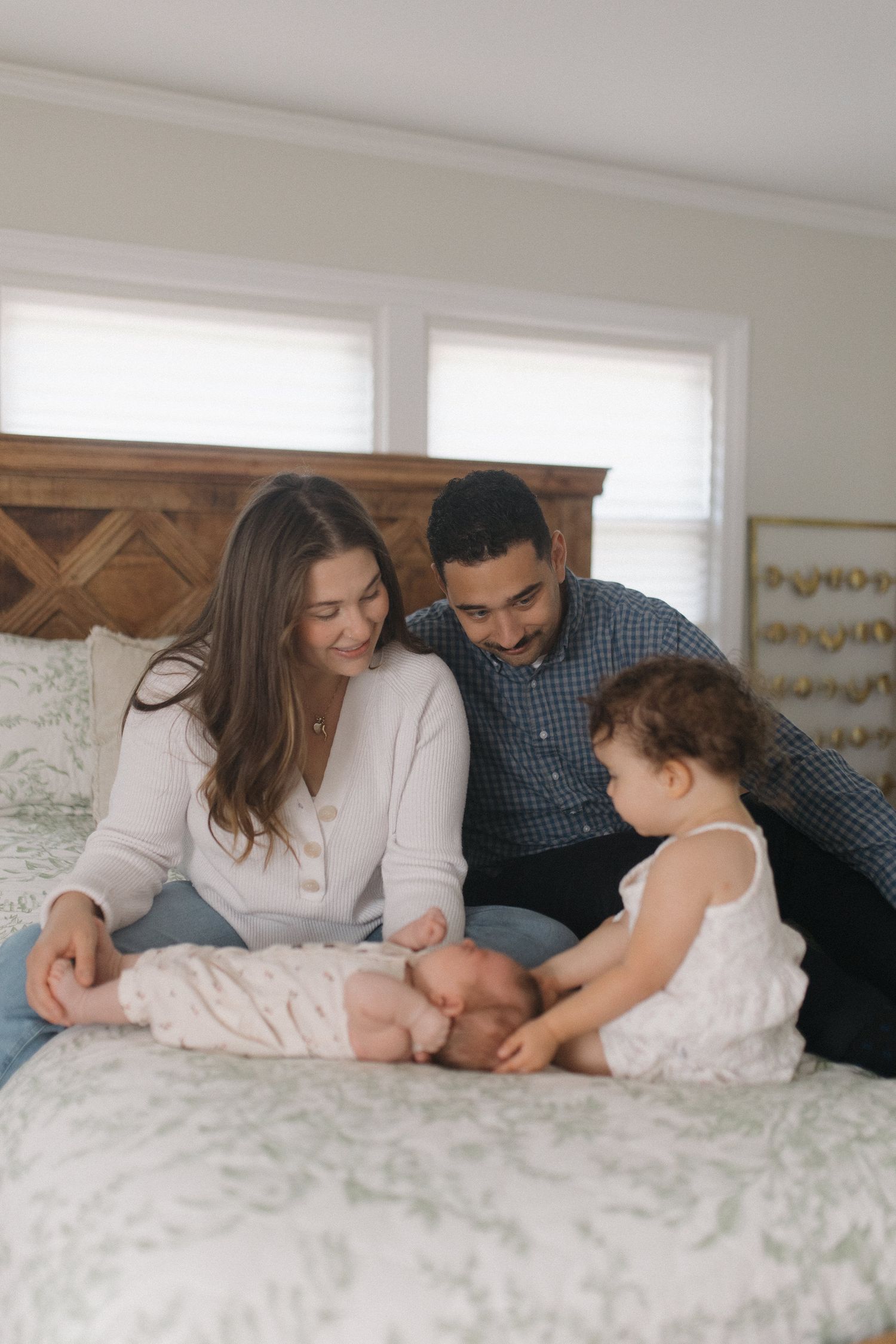 Young family with newborn and toddler sharing a joyful moment on a bed.