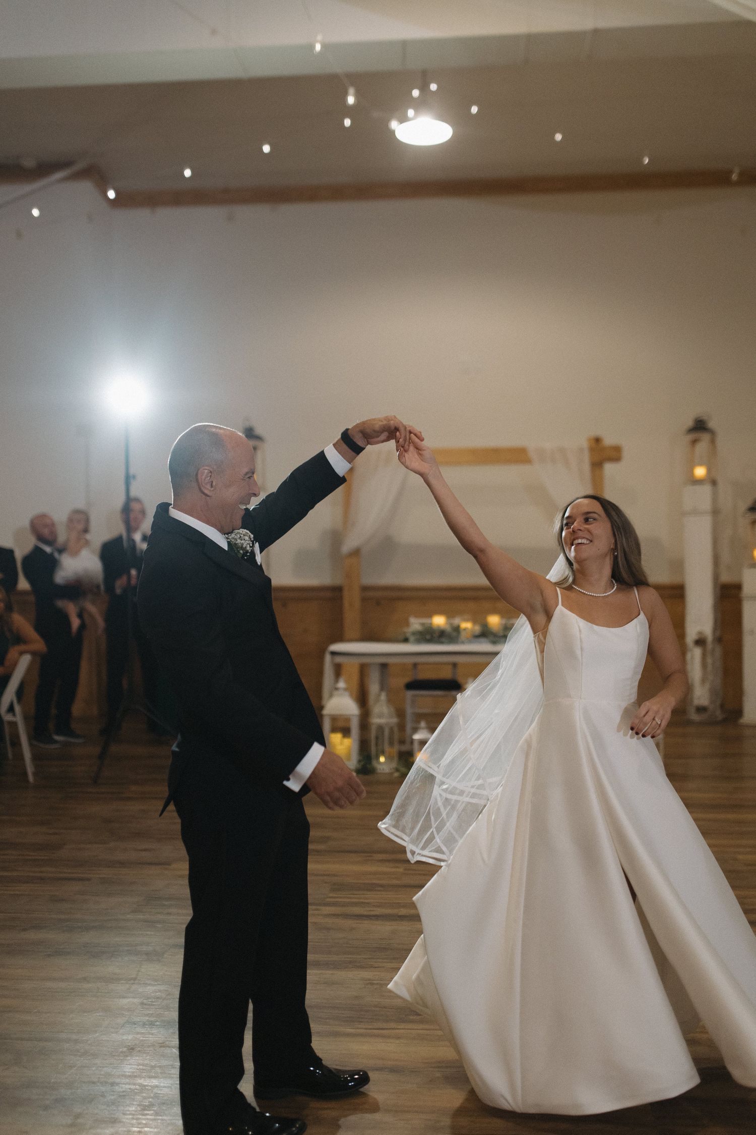 Bride and groom share their first dance, spinning joyfully in a warmly lit wedding reception hall.