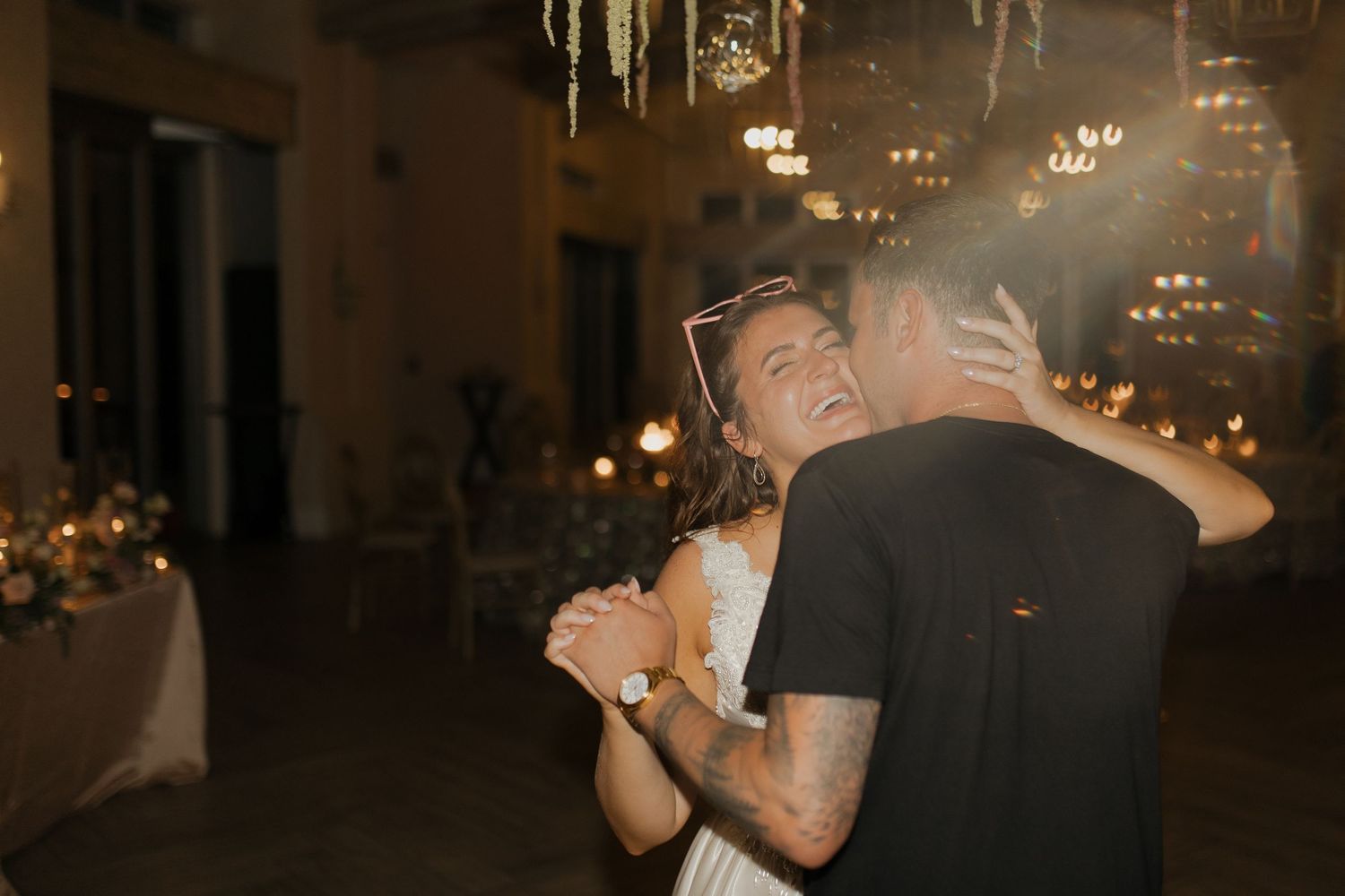Couple sharing their first dance at a romantic candlelit wedding reception with warm glowing lights.