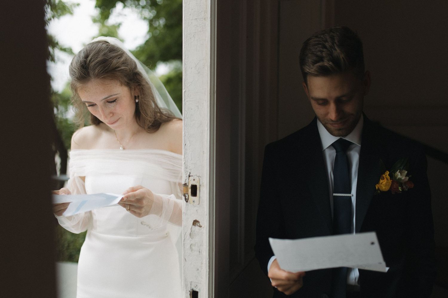 Bride and groom reading heartfelt letters to each other before their wedding ceremony, separated by a door.