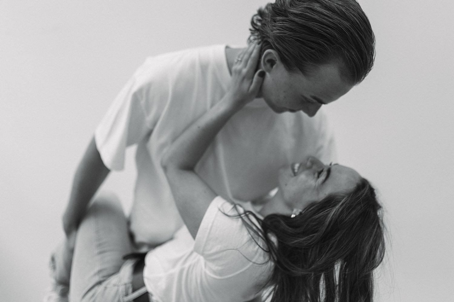 Black and white romantic photo of couple dancing, woman leaning back as man dips her gracefully.