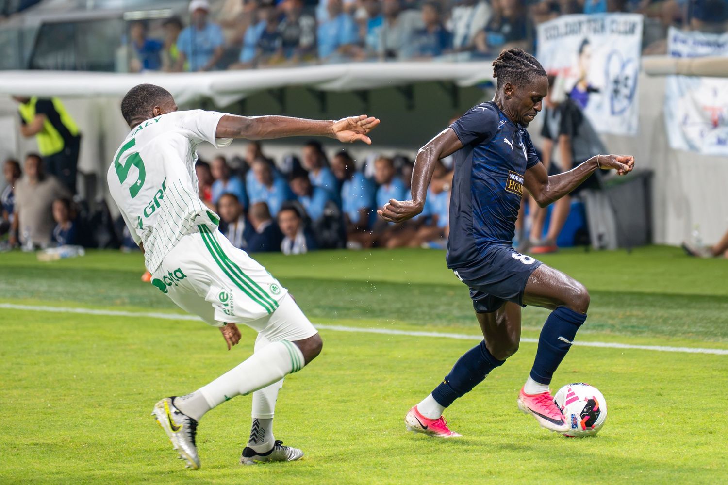Two soccer players compete for ball possession during a professional football league match.