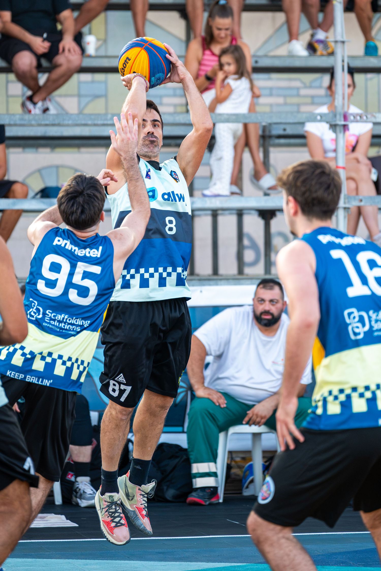 Player number 8 shoots over a defender during an outdoor 3x3 basketball tournament game.