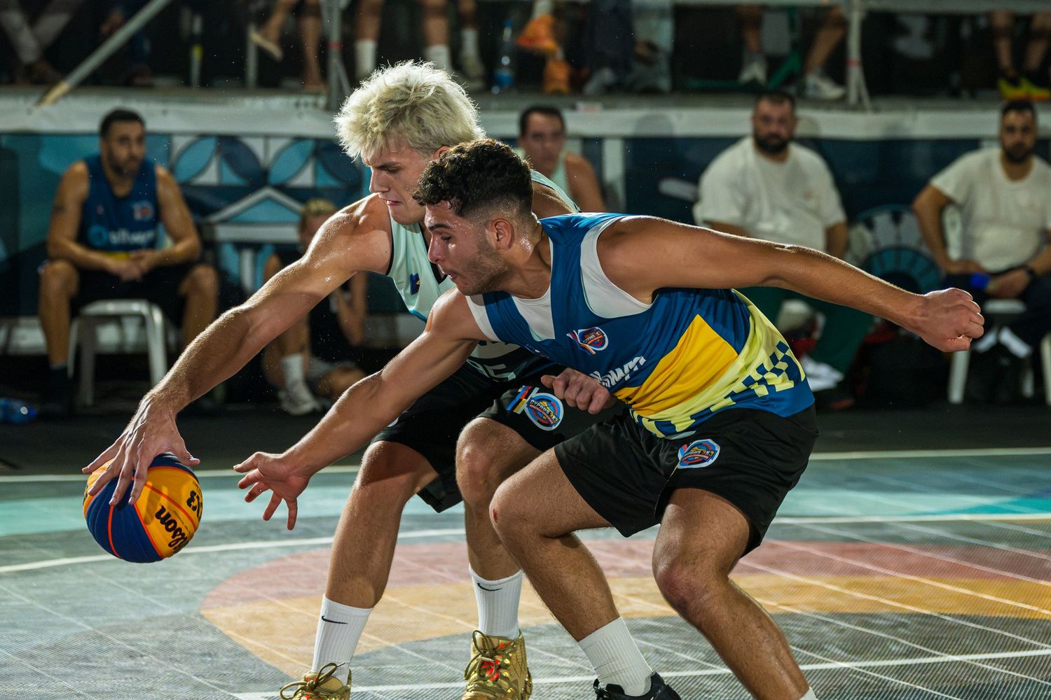Two basketball players battle for possession during an intense outdoor 3x3 basketball tournament game.