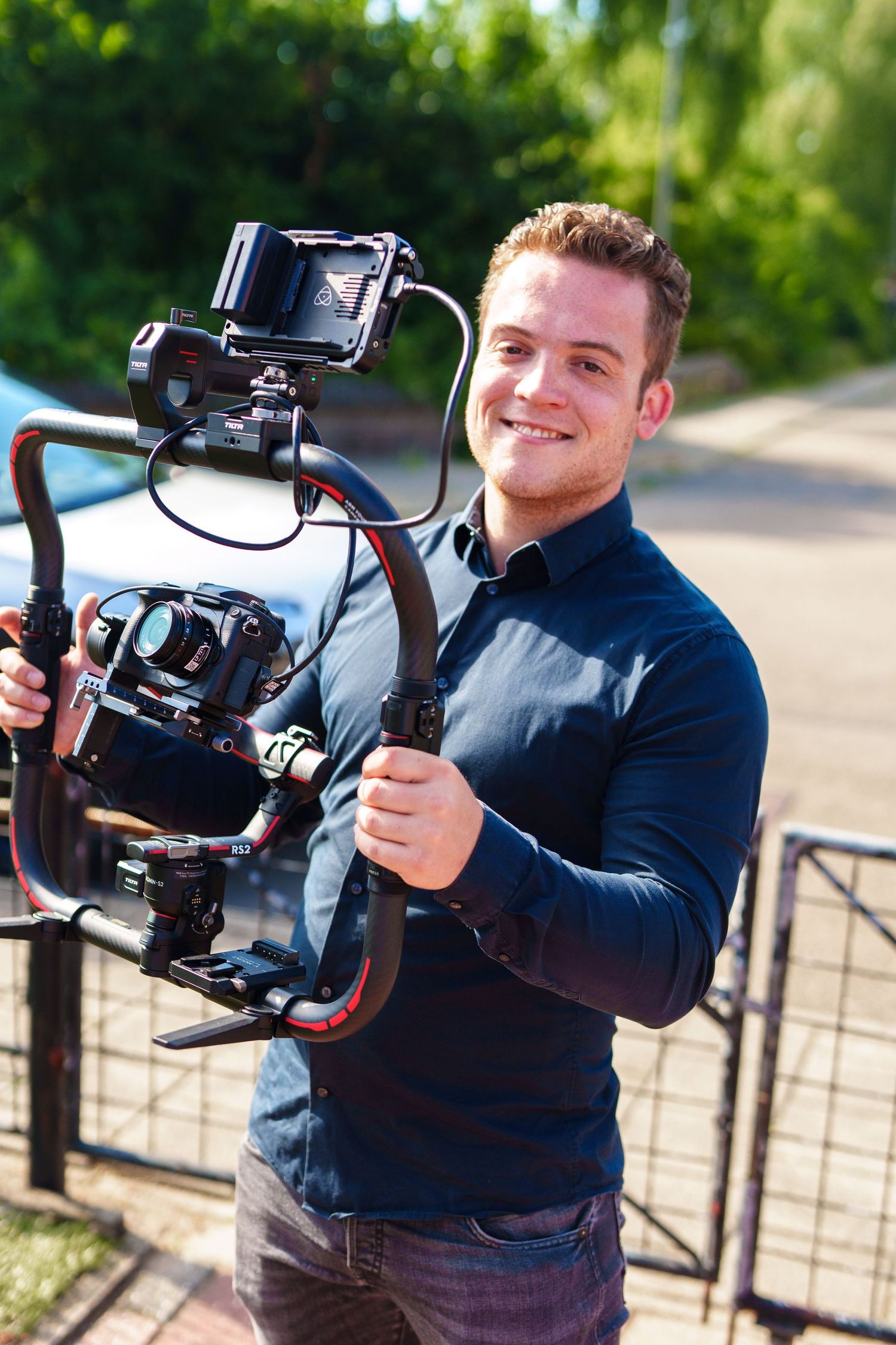 Videographer demonstrating professional camera movement techniques with handheld equipment outdoors.