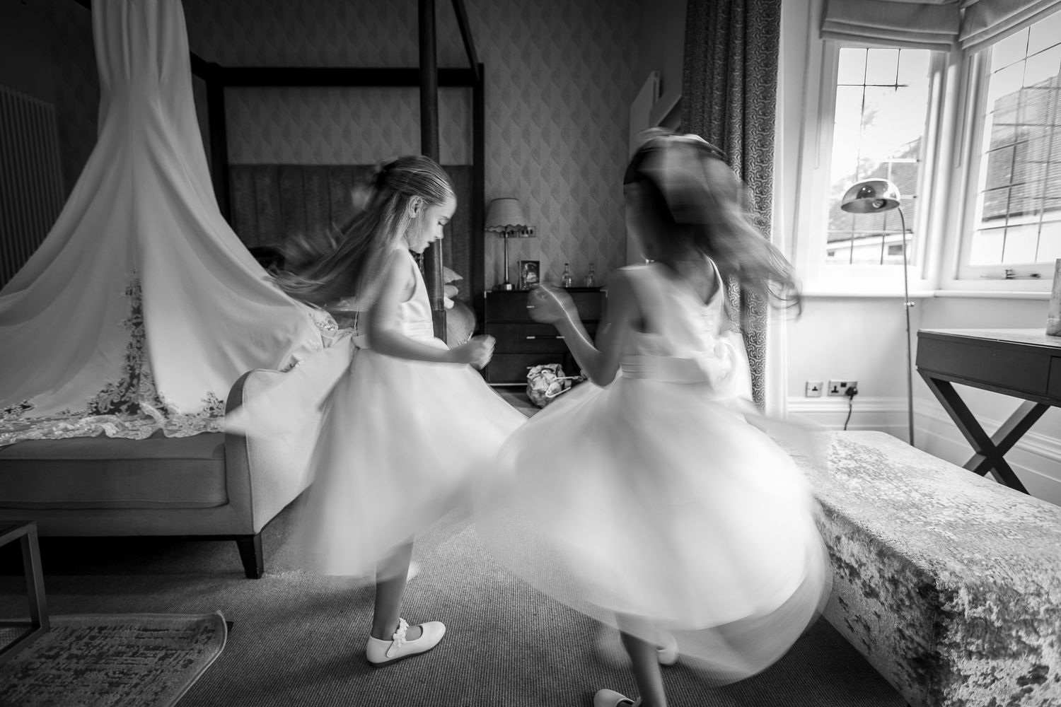 black and white image of two young bridesmaids dancing while getting ready for the wedding
