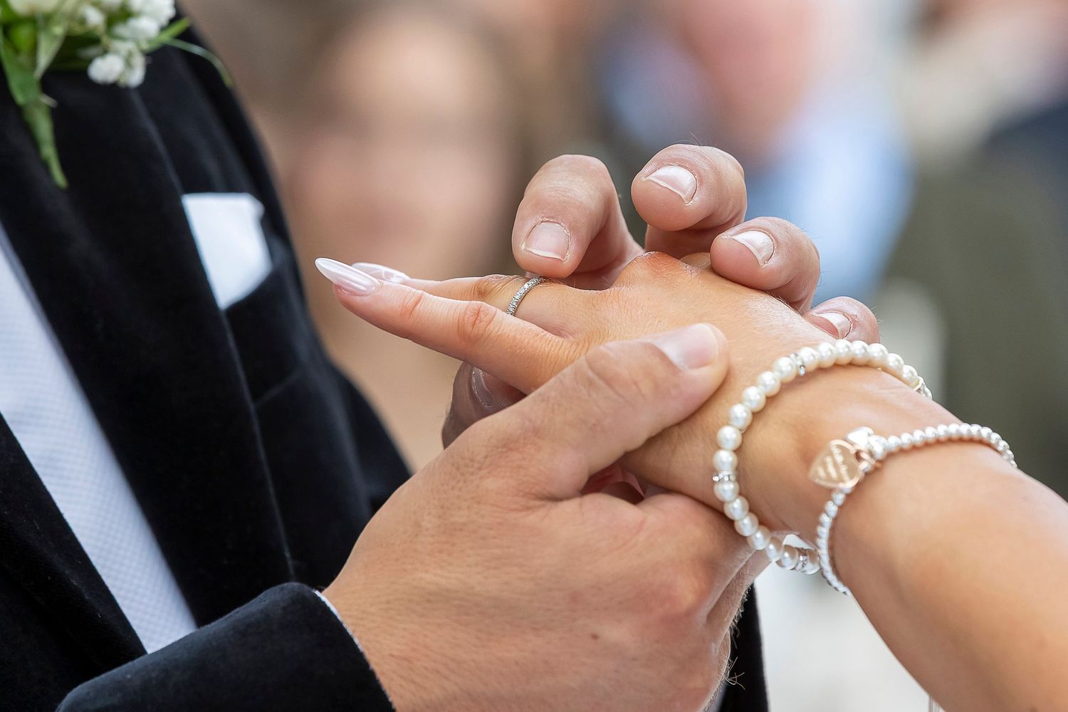 A close up of the groom putting the wedding ring on his bride