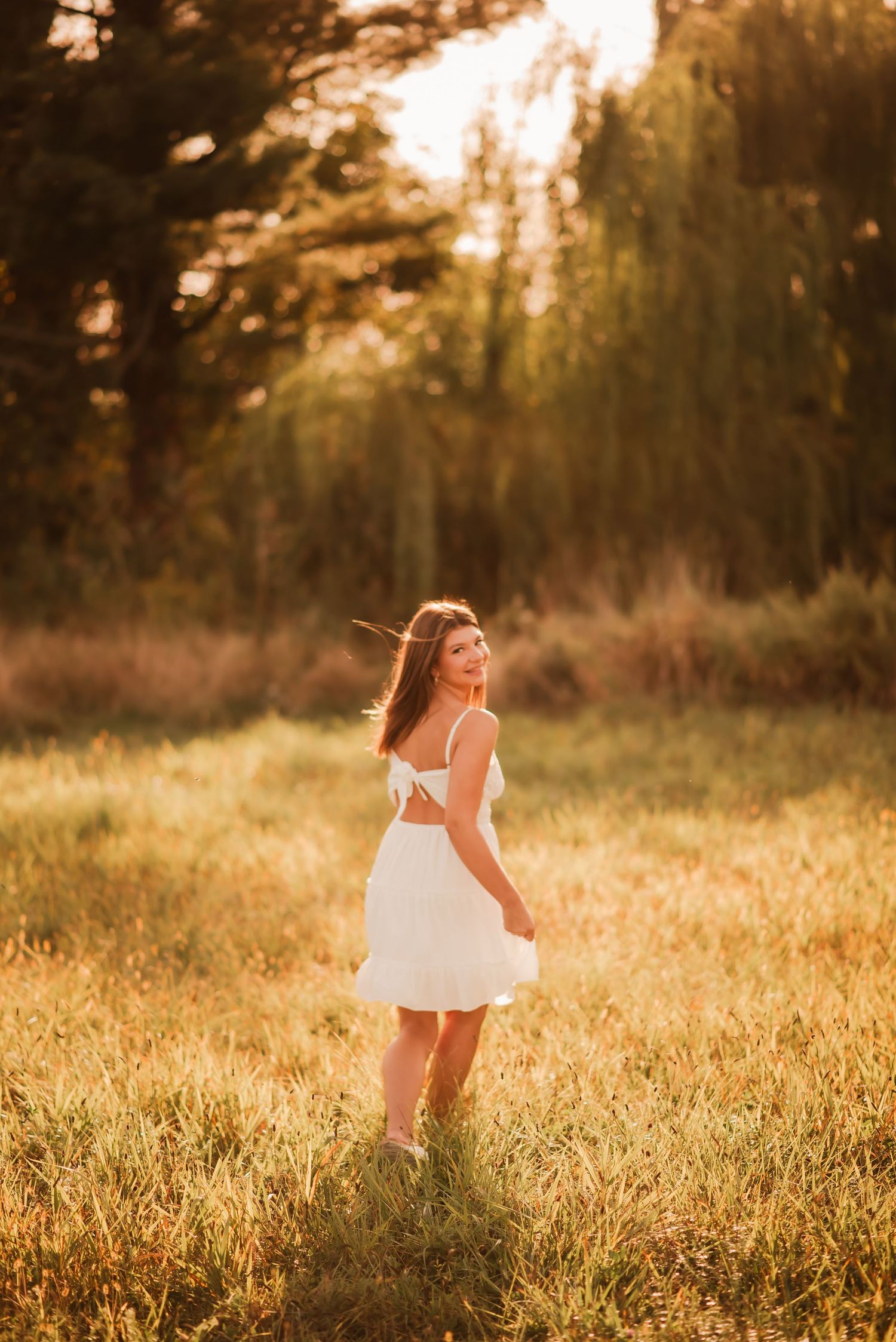 A child in a white dress twirls through a sunlit meadow during golden hour creating a dreamy summer scene.