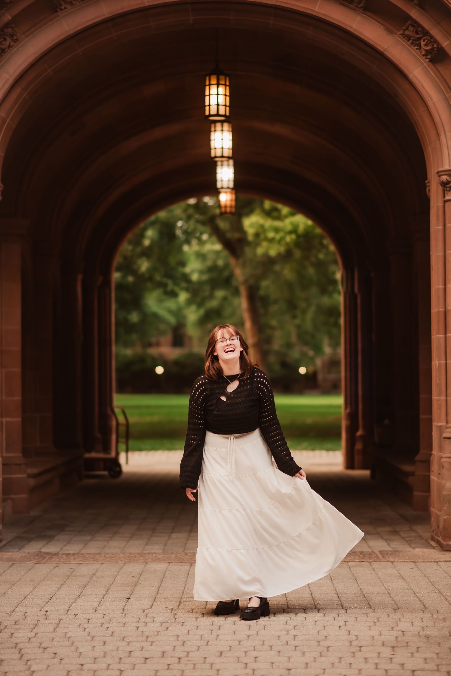 A series of five photos showing a joyful dance movement sequence under a stone archway passage.