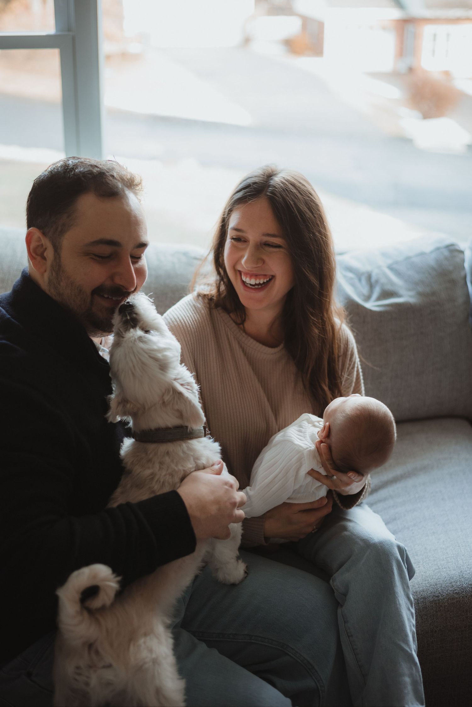 A couple sits on a couch sharing joyful moments with their small white dog in a series of candid photos.
