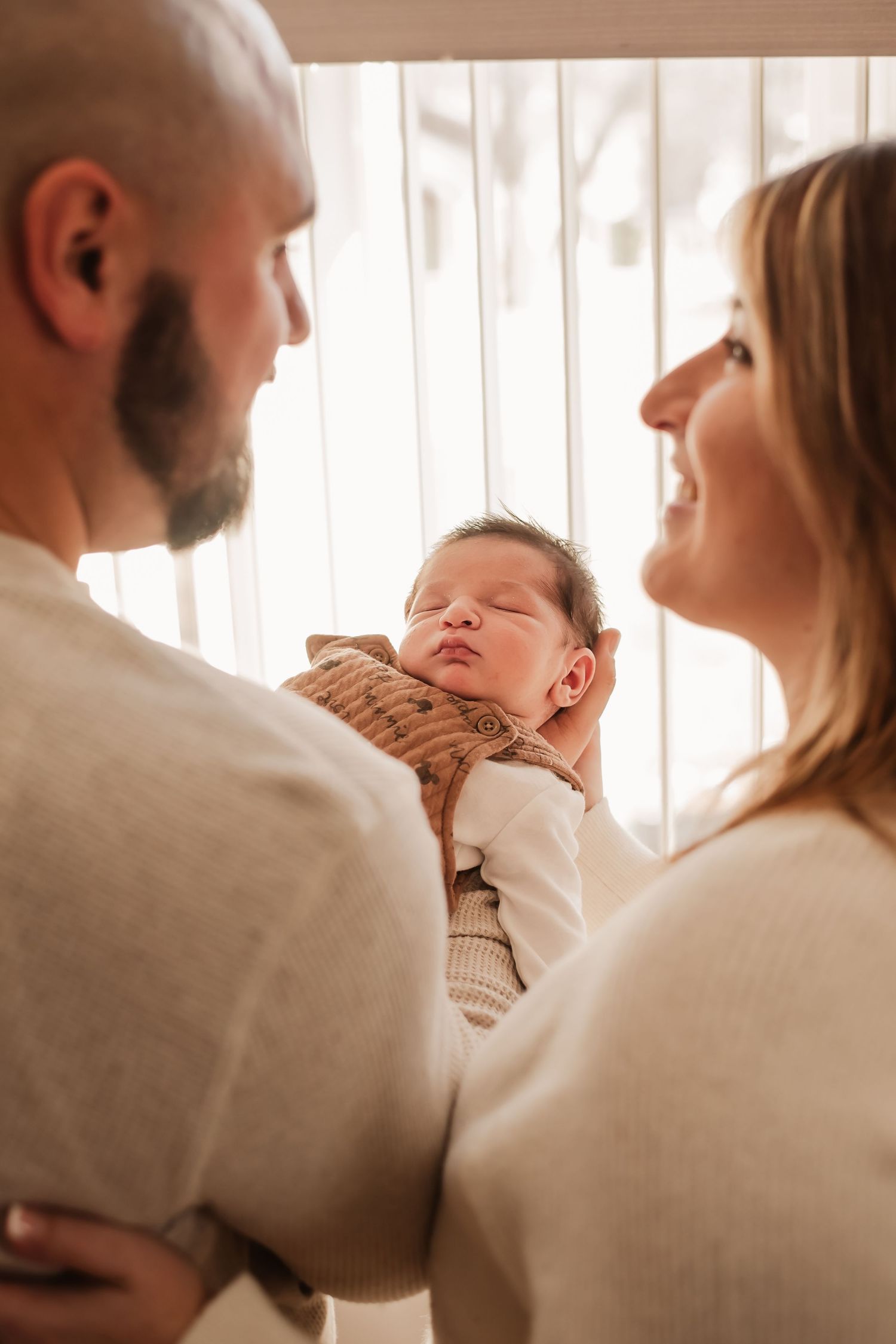 A series of intimate family portraits showing tender moments between parents and baby in warm, natural lighting.