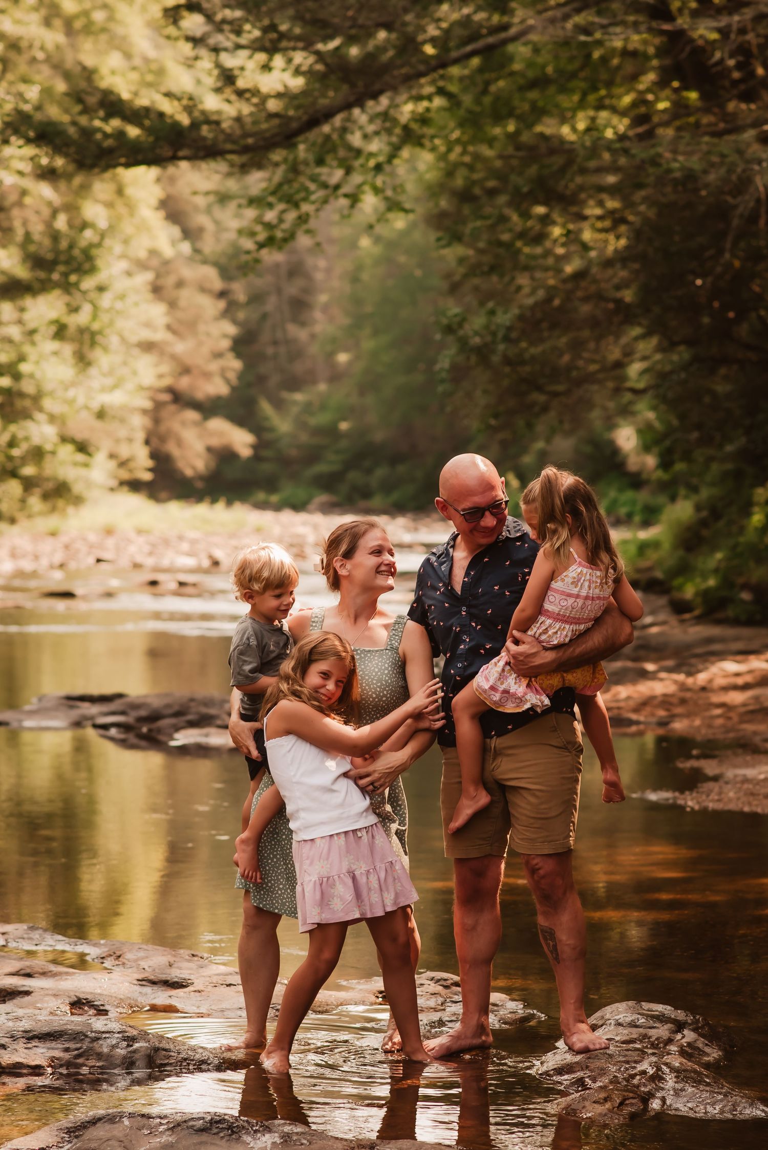 A playful family splashes and has fun together at a scenic creek on a warm summer day.