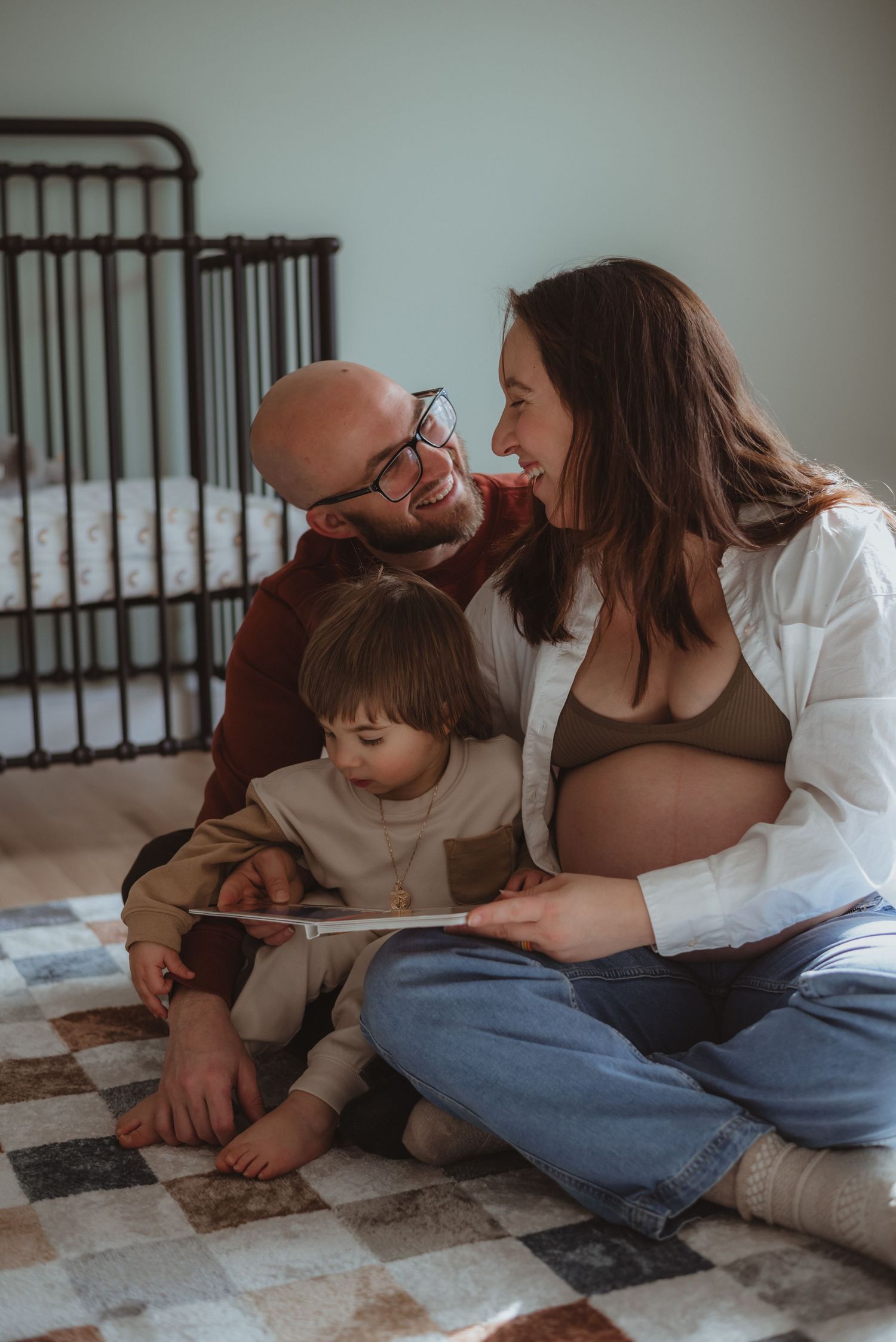 Family relaxing together on a cozy rug at home, sharing tender moments in a casual indoor setting.