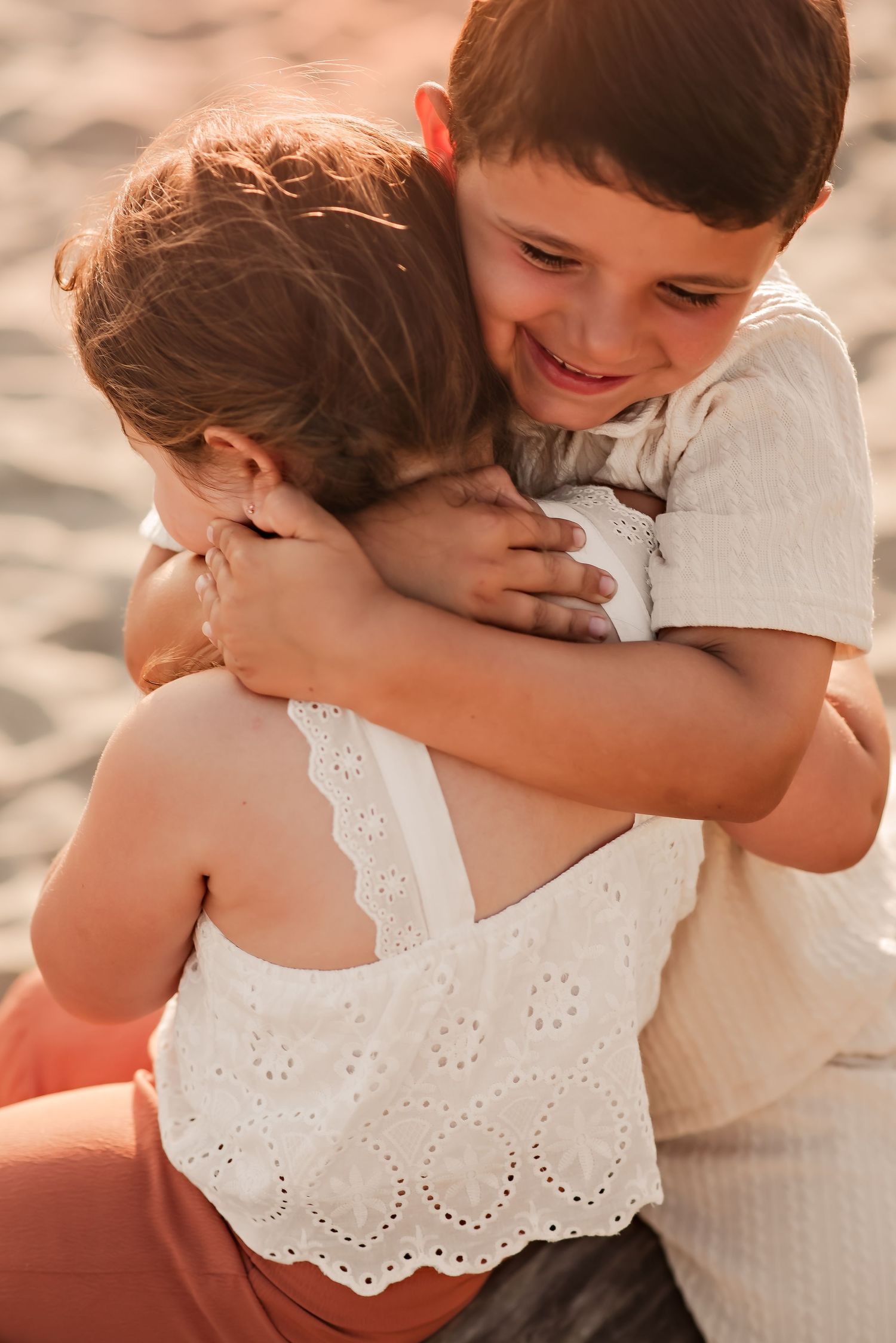 A heartwarming sequence of close-up photos showing tender embraces and playful moments between siblings in white outfits.