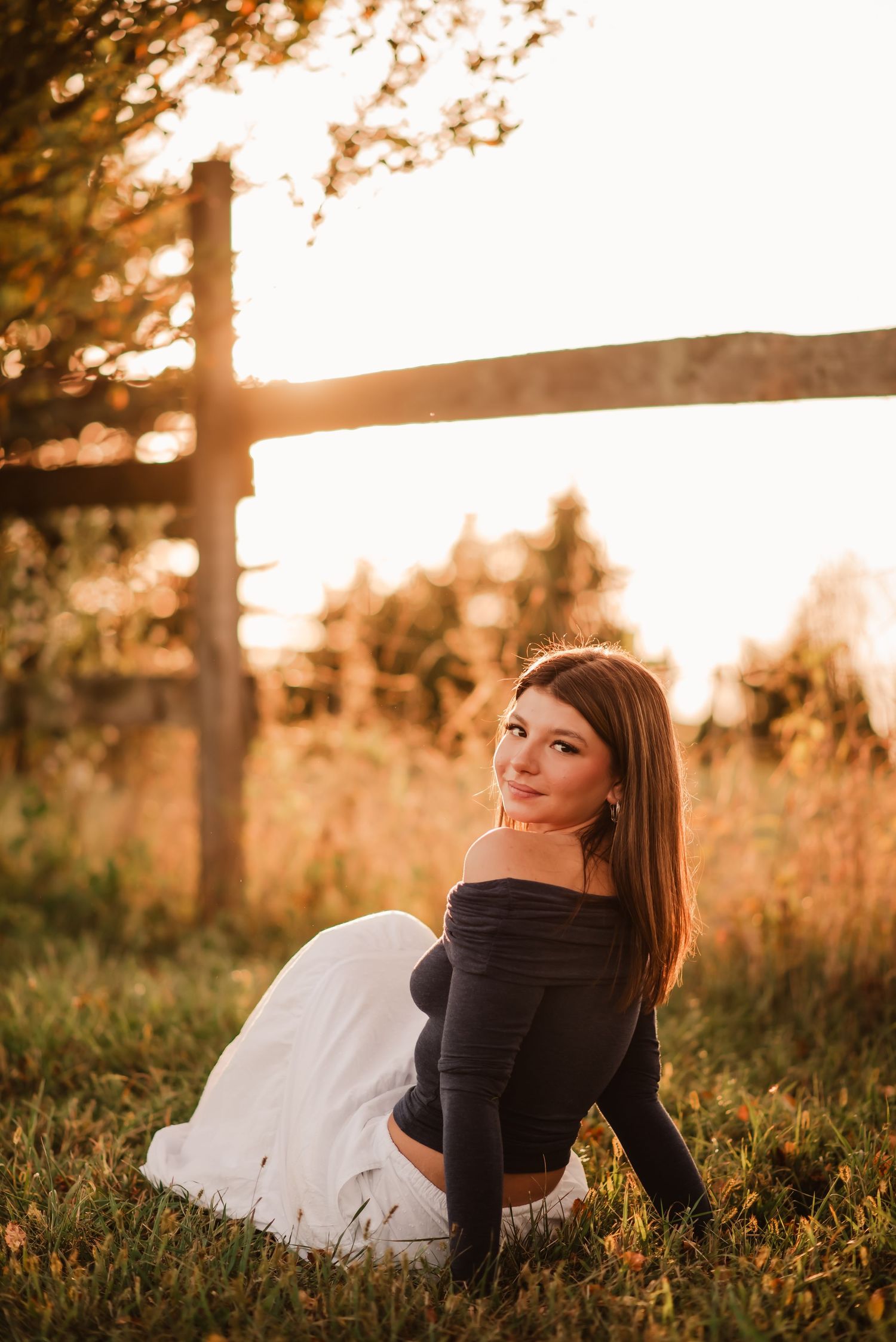 Person laying in grass during golden hour sunset with warm backlighting and dreamy atmosphere.