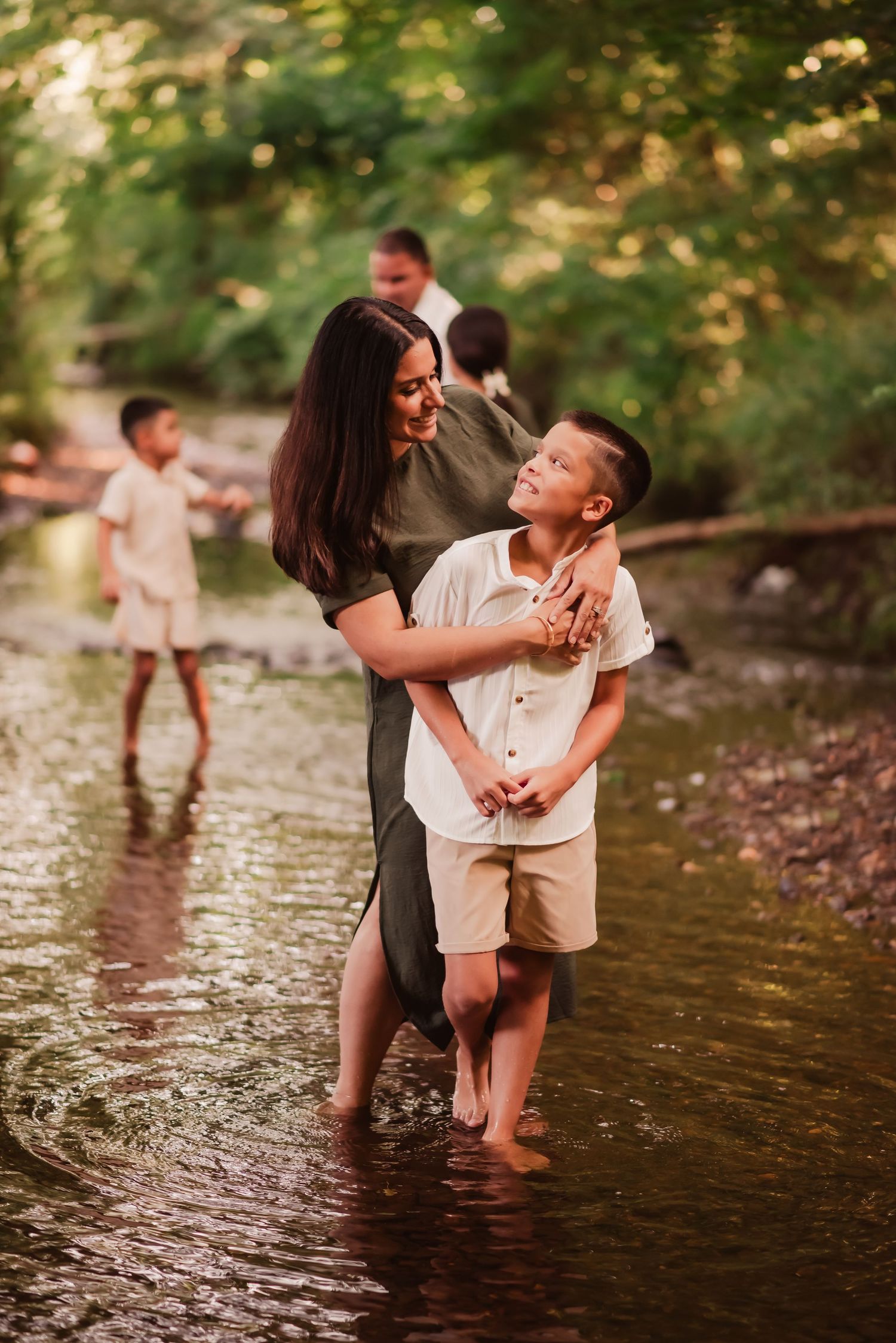 A couple and child play together in a shallow creek on a warm summer day, creating joyful moments in nature.