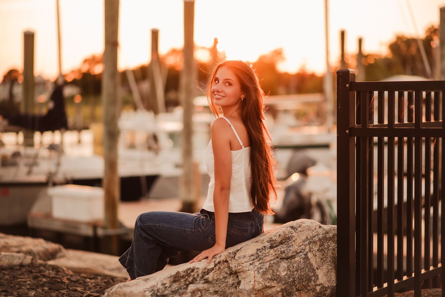 Person practicing yoga poses at sunset on a wooden dock by the water with boats in background.