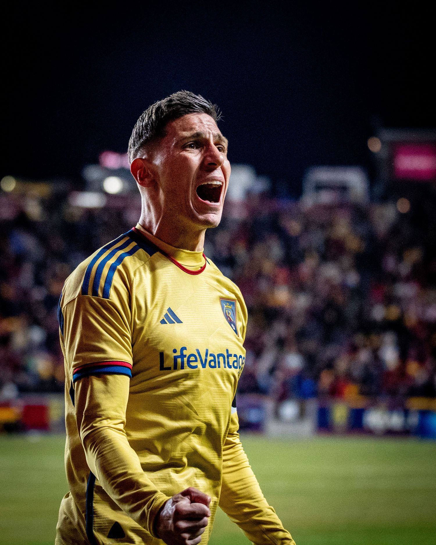 Soccer player in yellow jersey celebrates passionately during match with intense emotional display.