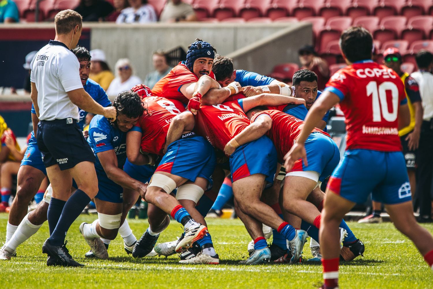 Rugby players from opposing teams engage in a scrum formation during a competitive match on the field.