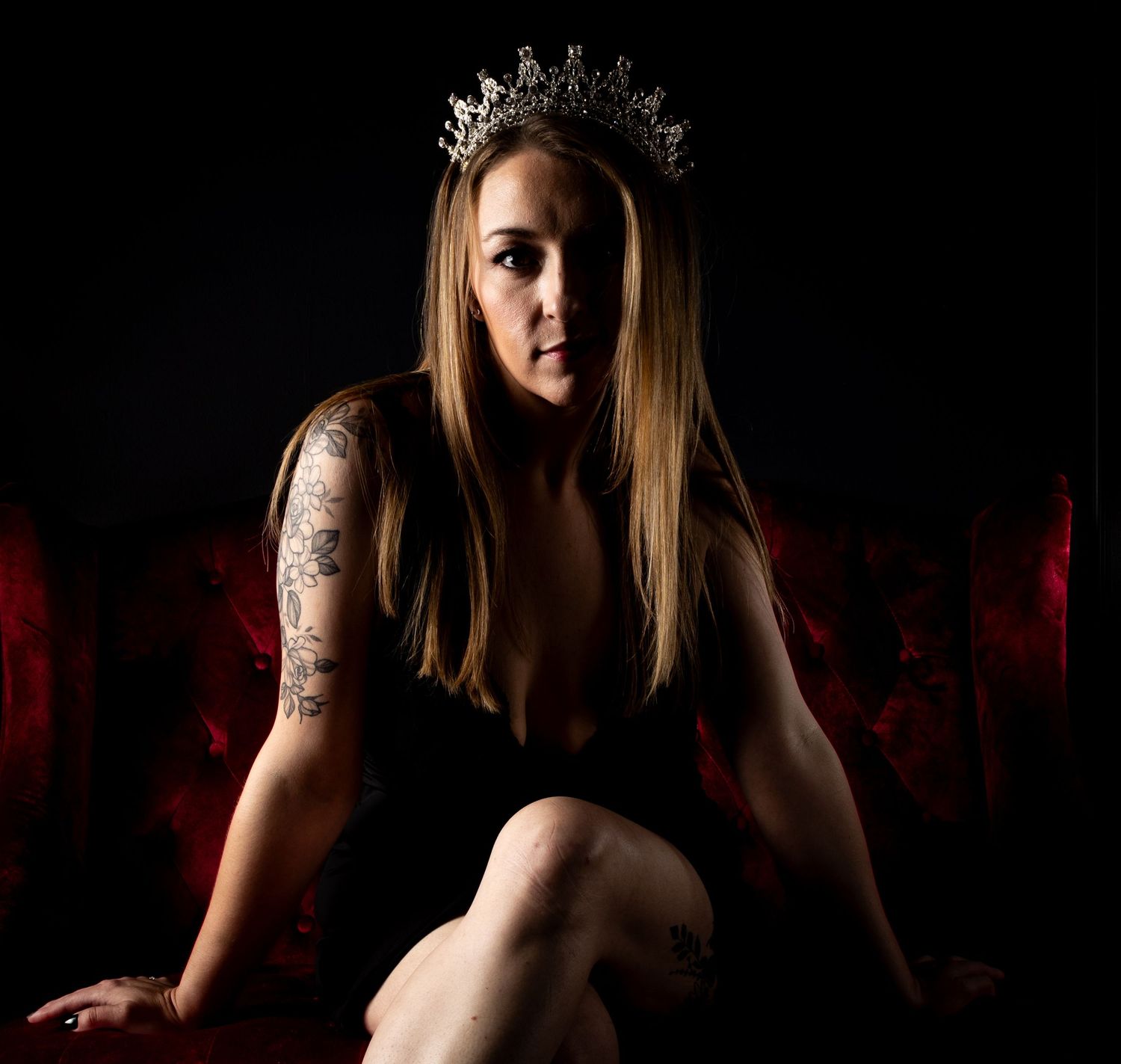 Intimate boudoir portraits on red velvet furniture with dramatic lighting.