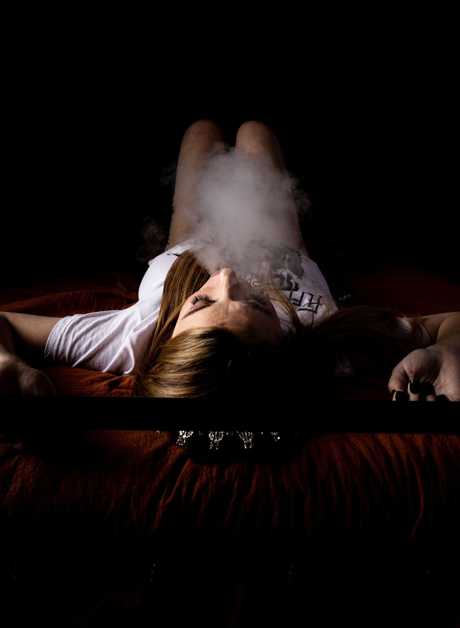 Atmospheric boudoir photos with smoke effects on dark bedding.