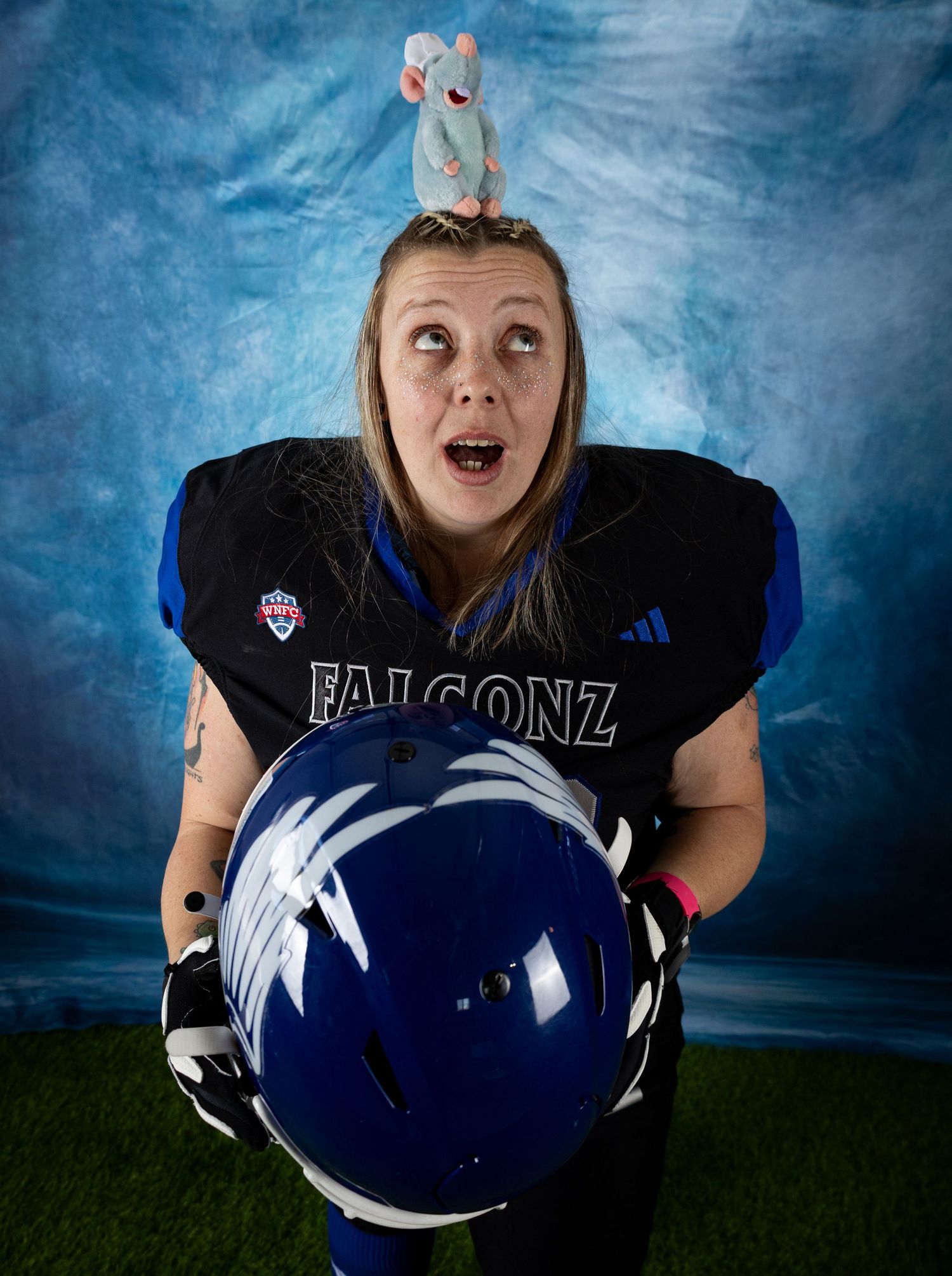 Football player in black jersey and blue helmet poses for a series of dynamic portraits against a stormy sky background.