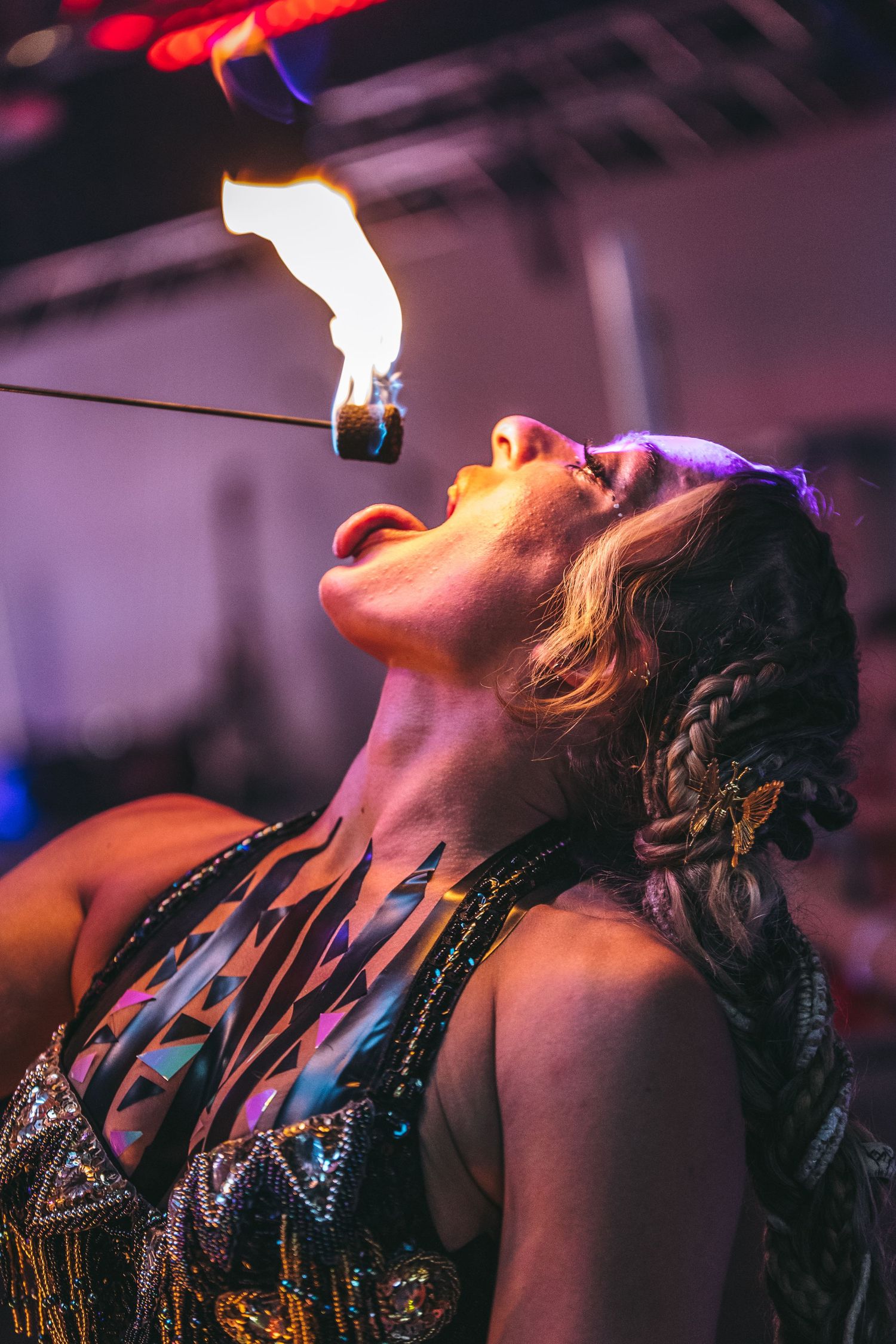 A dancer performs with dramatic lighting, head tilted back in an expressive pose with braided hair and sparkling costume.